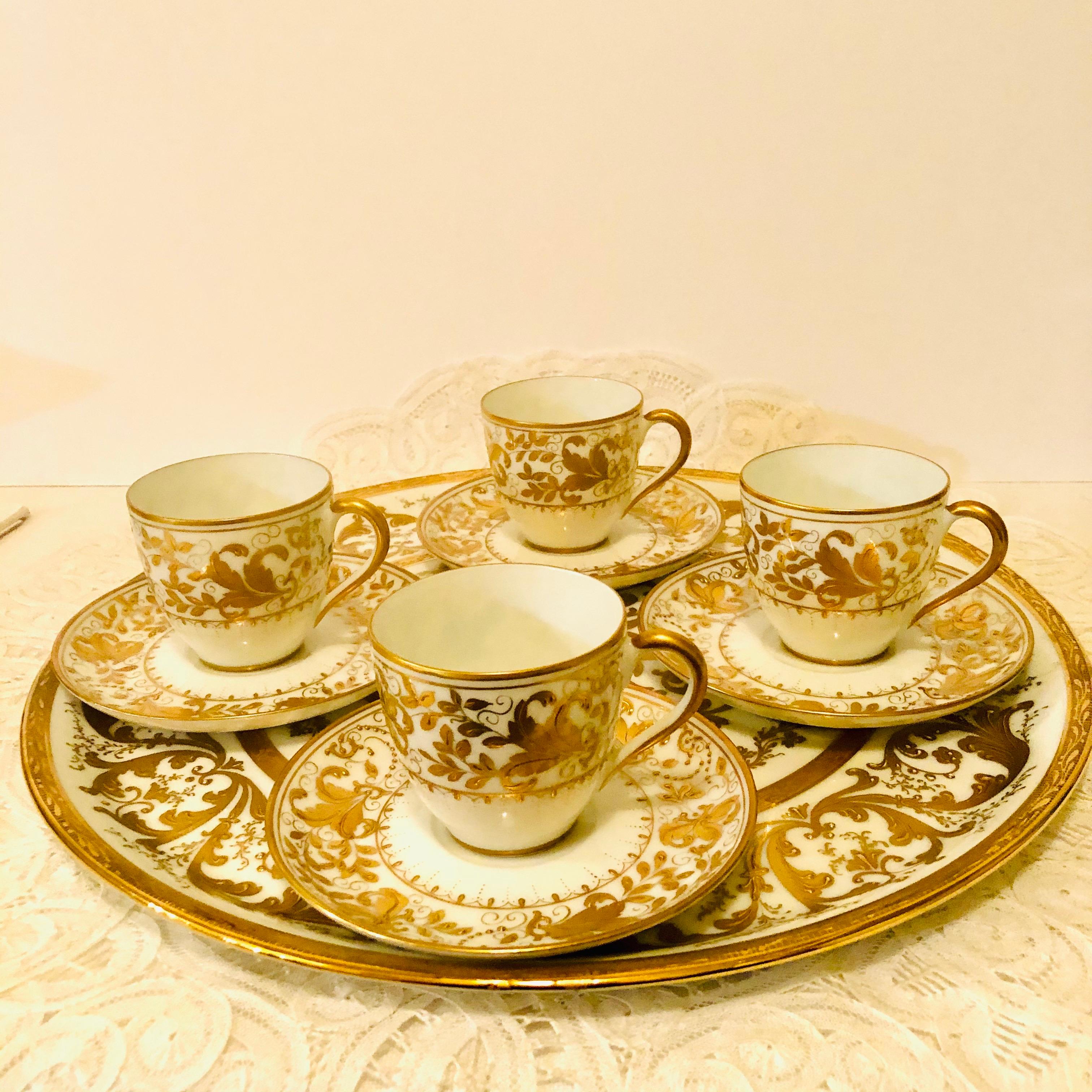 This is an exquisite Le Tallec set that includes four demitasse cups and saucers with a tray with a matching pattern. All the cups and saucers and the tray are embellished in raised profuse gilding with curves and scrolls in a rococo style. The tray
