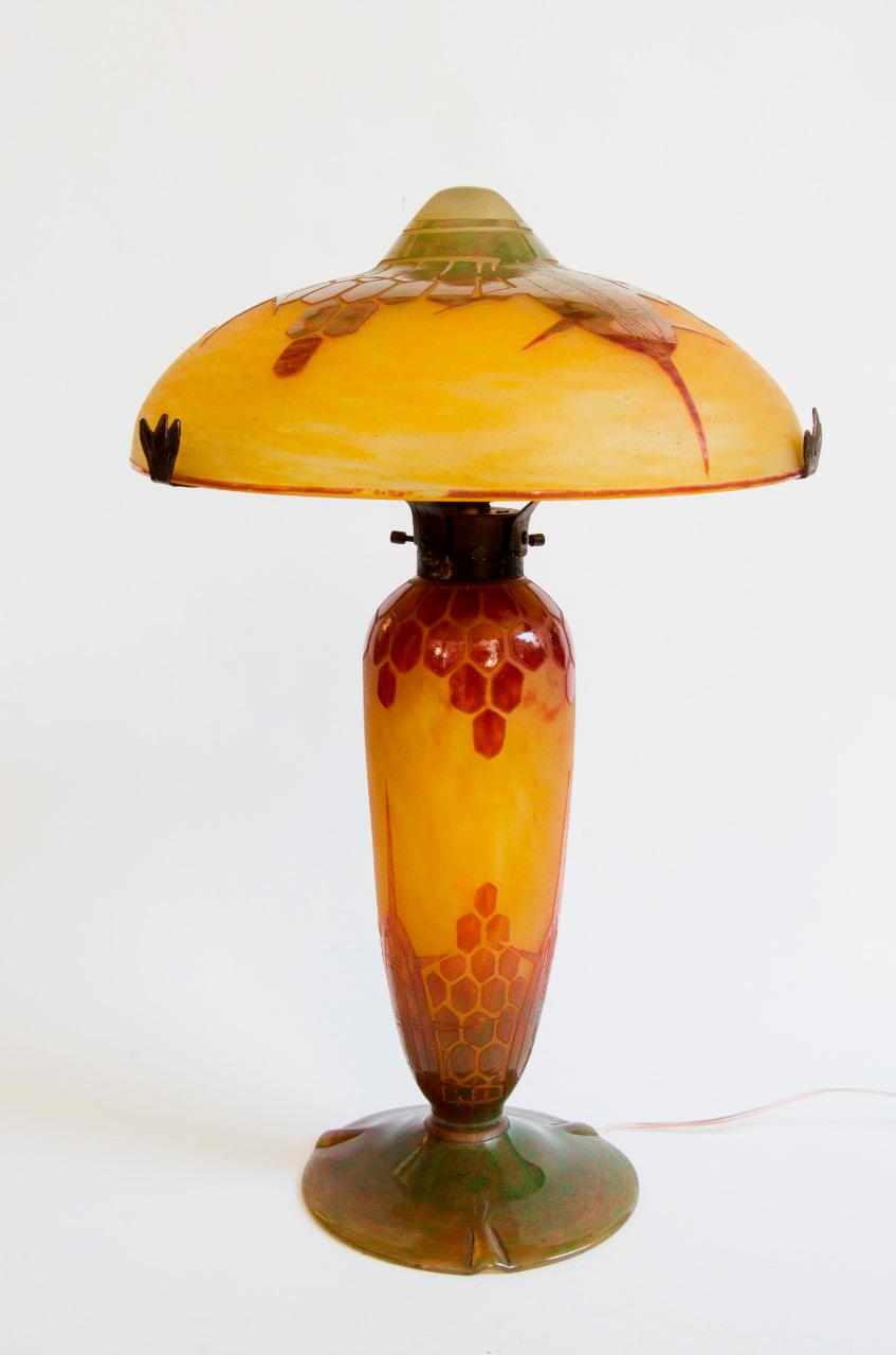 Une merveilleuse lampe en verre Art Déco du début du 20ème siècle, avec des motifs gravés sur un fond orange, avec d'excellentes couleurs et détails. Le luminaire est en fer forgé martelé, câblé à nouveau pour l'électricité moderne et testé. Le pied
