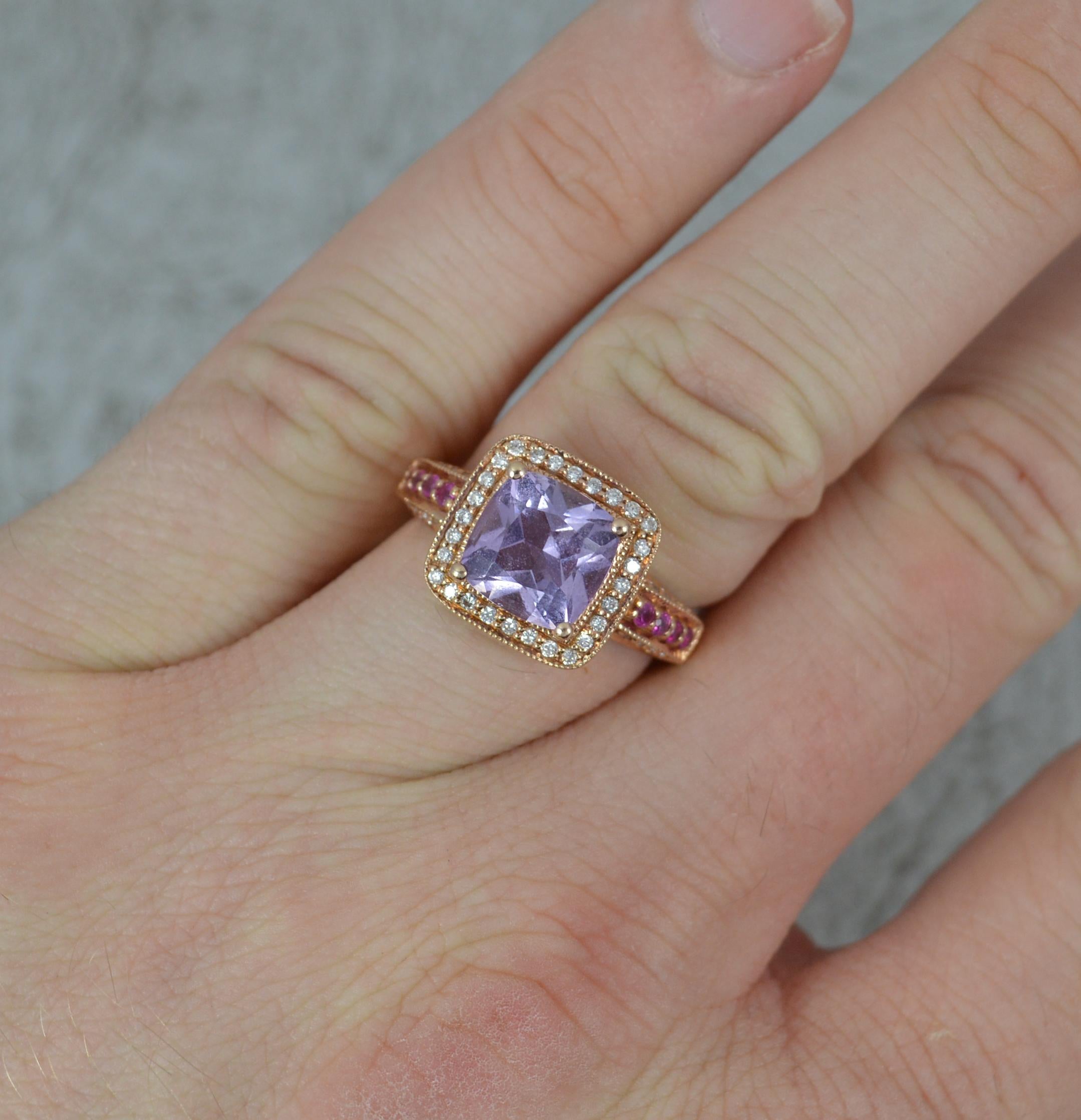 A beautiful Amethyst, Ruby and Diamond ring.
Solid 14 carat rose gold example with fine beaded finish.
Designed with a princess cushion cut amethyst to centre in four claw setting. A full diamond border. With rubies and diamonds to the