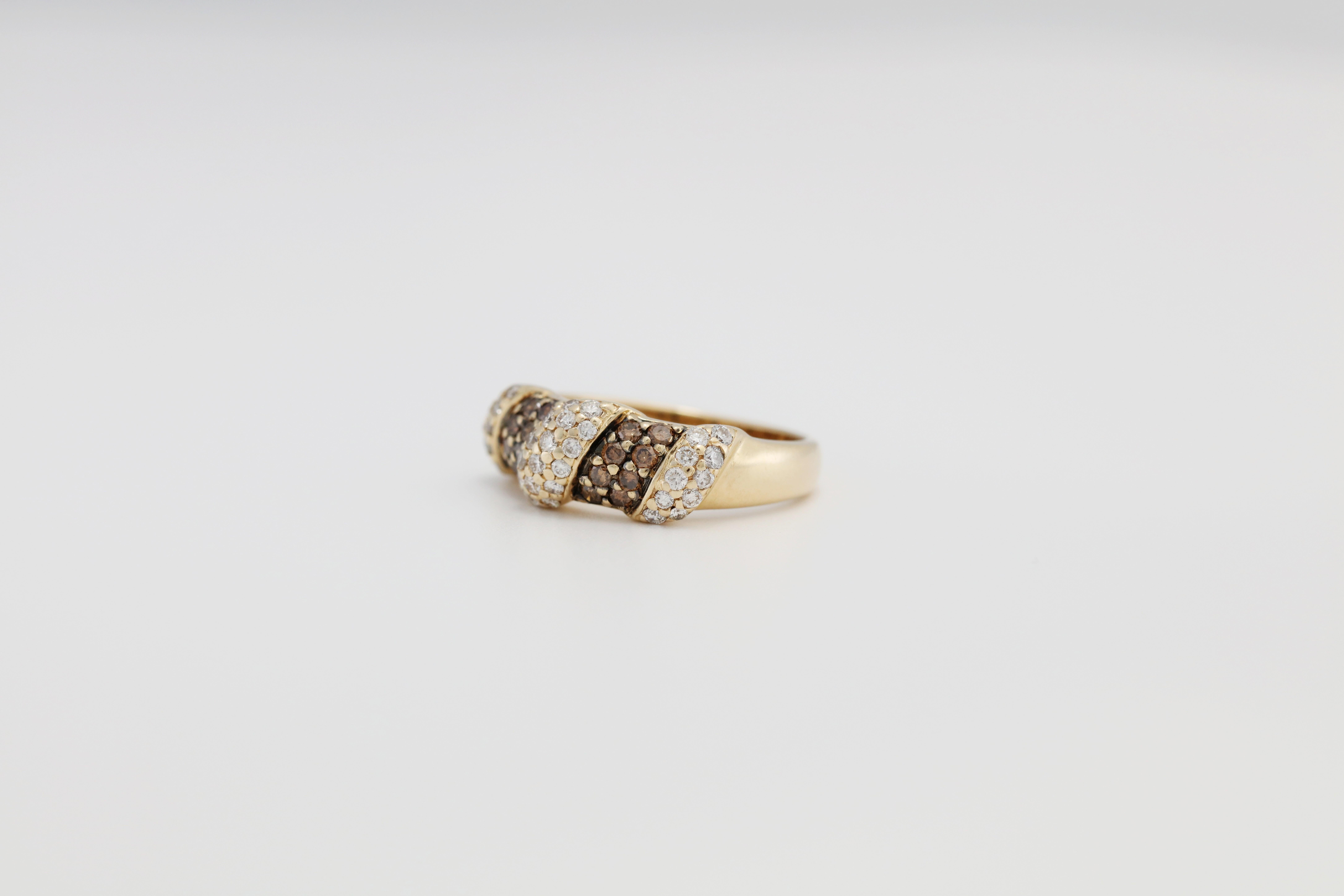 This stunning Le Vian ring is crafted in 14k yellow gold and features a bold, sculptural design with a signature crossover motif. The band is encrusted with rows of round-cut white and chocolate diamonds, creating a striking contrast and luxurious
