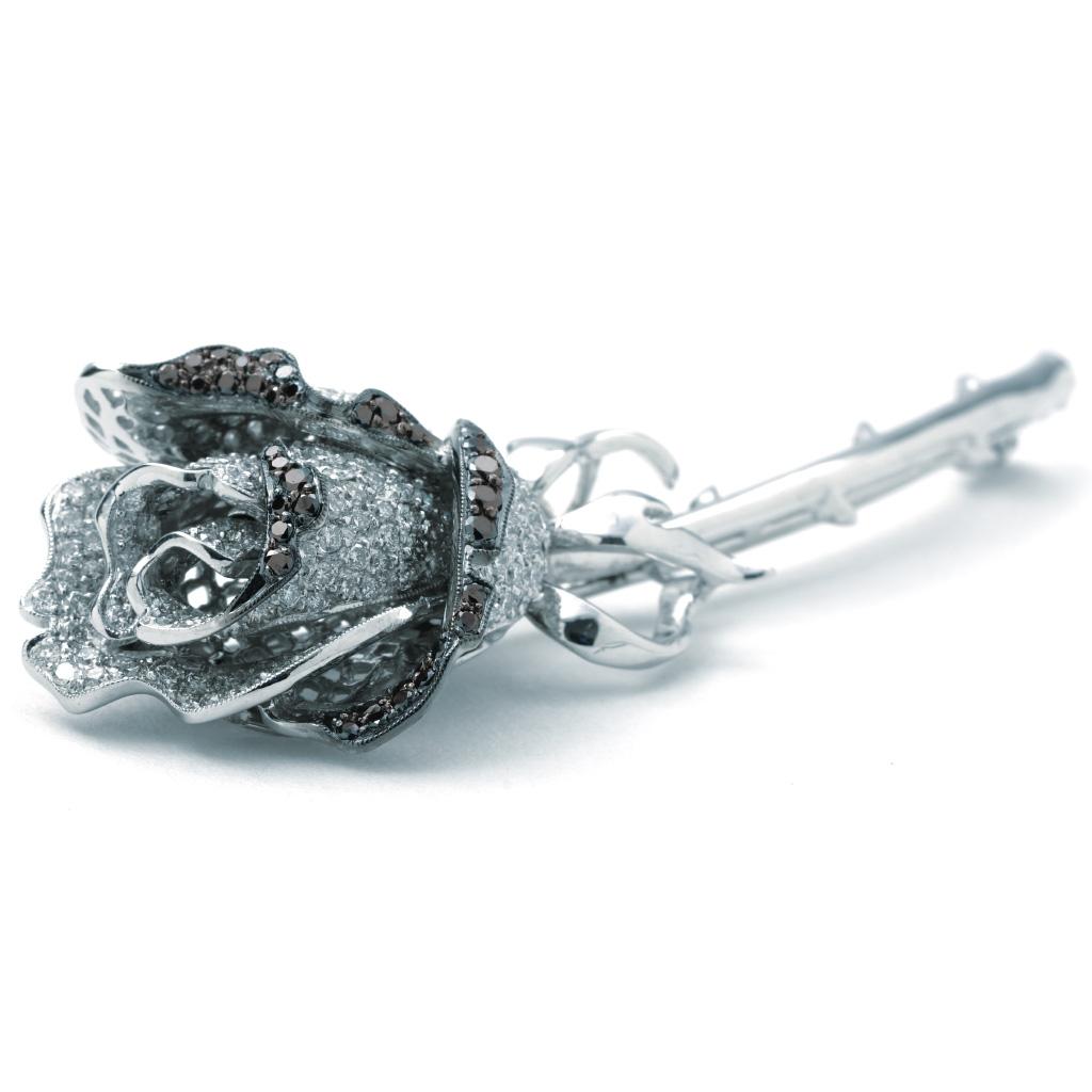 Previously-owned Levian Black and White Diamond Rose Collection pin. The pin is 3 inches in length, made of 18K white gold, and weighs 12.70 DWT (approx. 19.75 grams). It also has 37 Black-color diamonds weighing 0.65 CTTW, and 213 G/H-color,