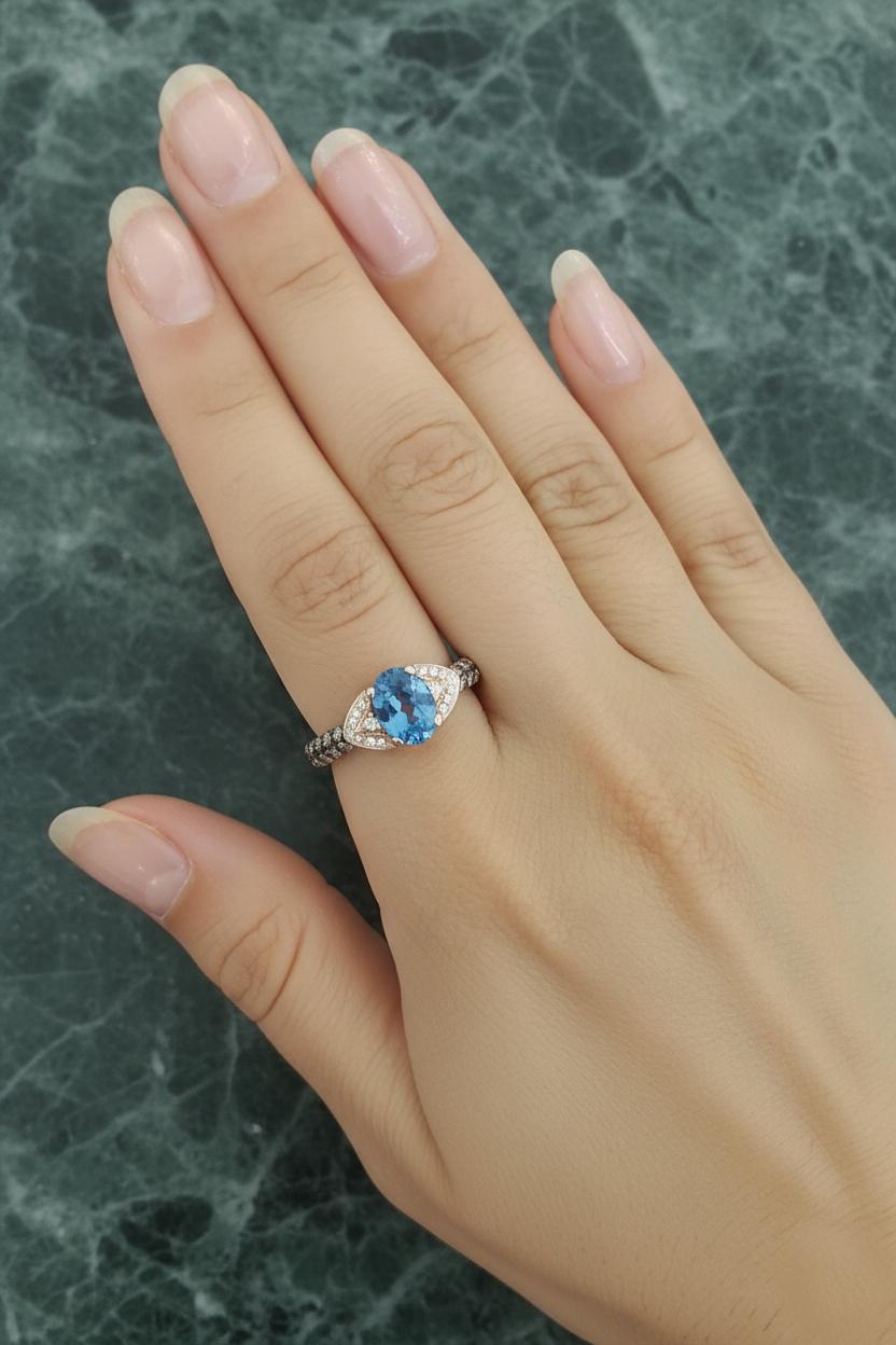 Eine wunderschöne und lebendige Kreation von Le Vian, die die für die Marke typische Kombination aus lebendigen Farben und luxuriösem Design zeigt.

In der Mitte des Rings liegt ein natürlicher Blautopas im Ovalschliff, der in einem bezaubernden