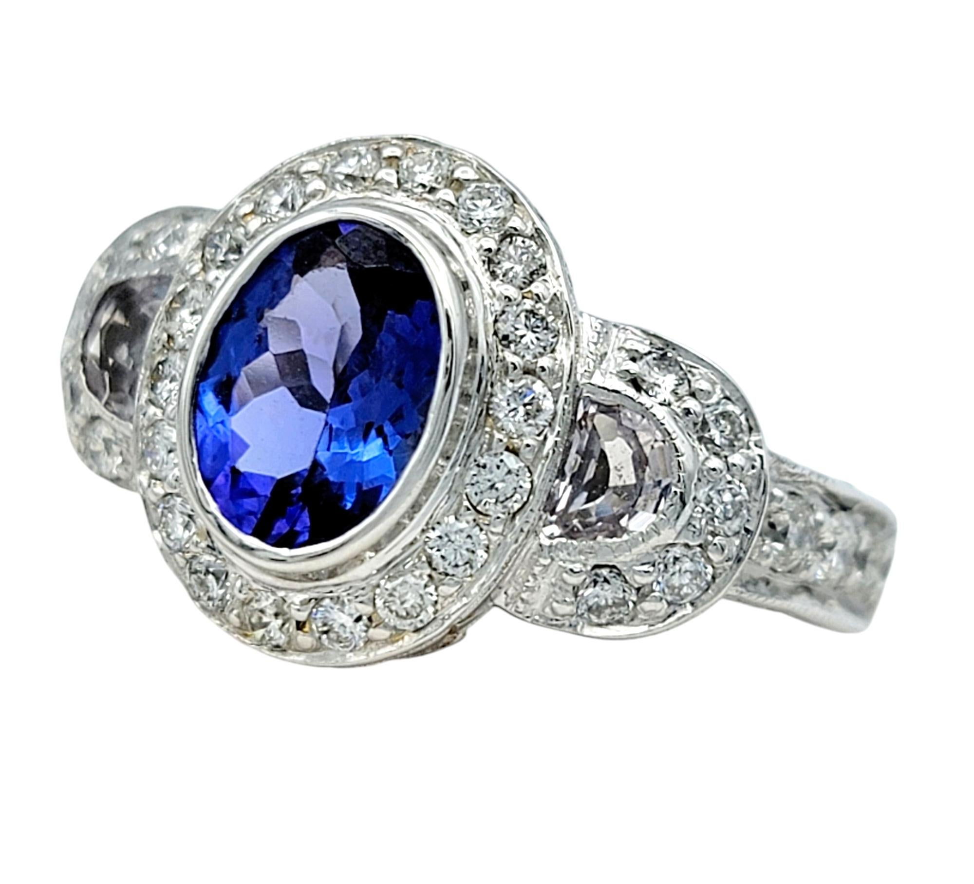 Ti presentiamo questo lussuoso anello a tre pietre con tanzanite e diamanti di Le Vian, una straordinaria miscela di eleganza e maestria. Al centro, la splendida tanzanite ovale abbaglia con profonde e ipnotiche sfumature blu-viola, splendidamente