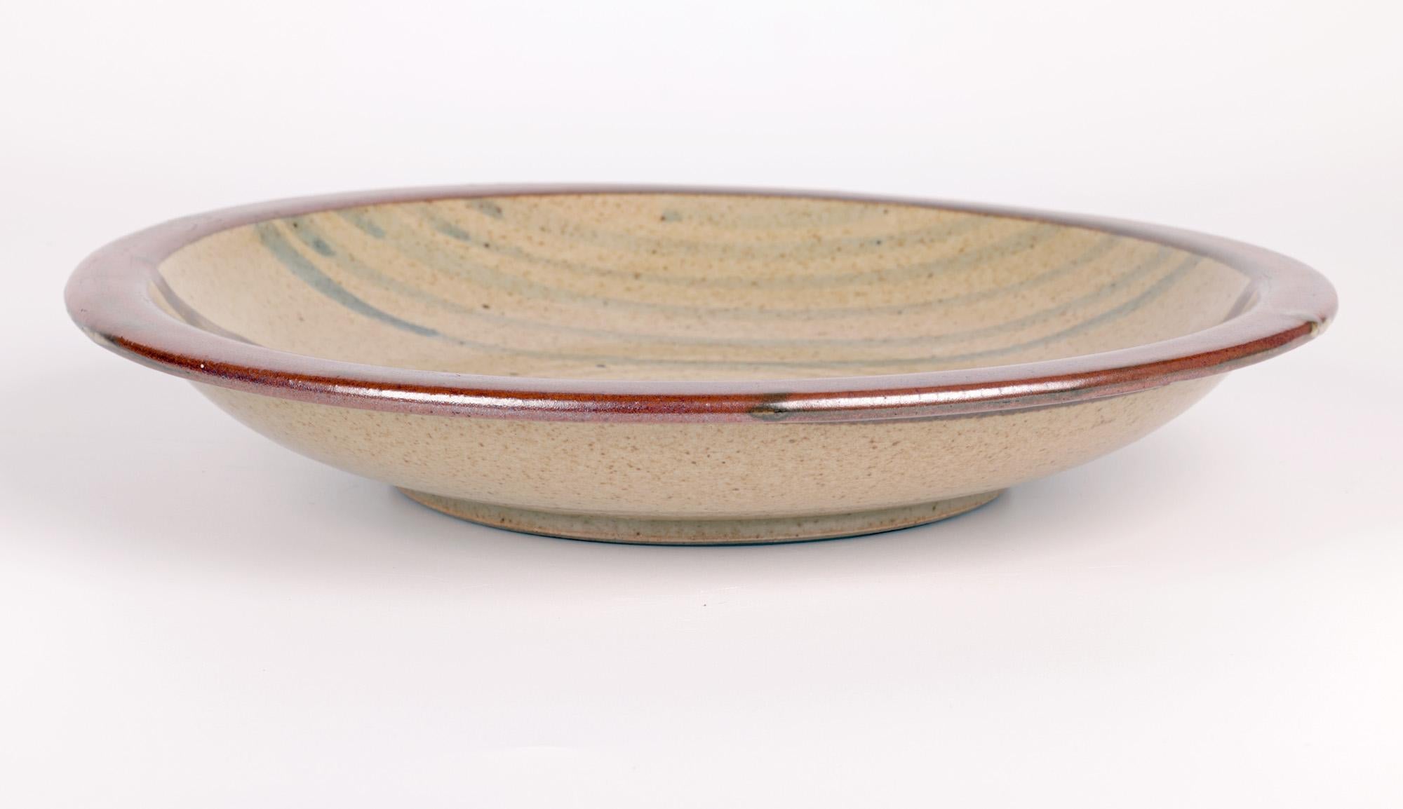 A large and impressive Leach Pottery trailed design cake plate made at St Ives, Cornwall and dating from the 20th century. This sought after plate is finely and heavily made standing on a narrow round unglazed foot with a raised rim with a shaped