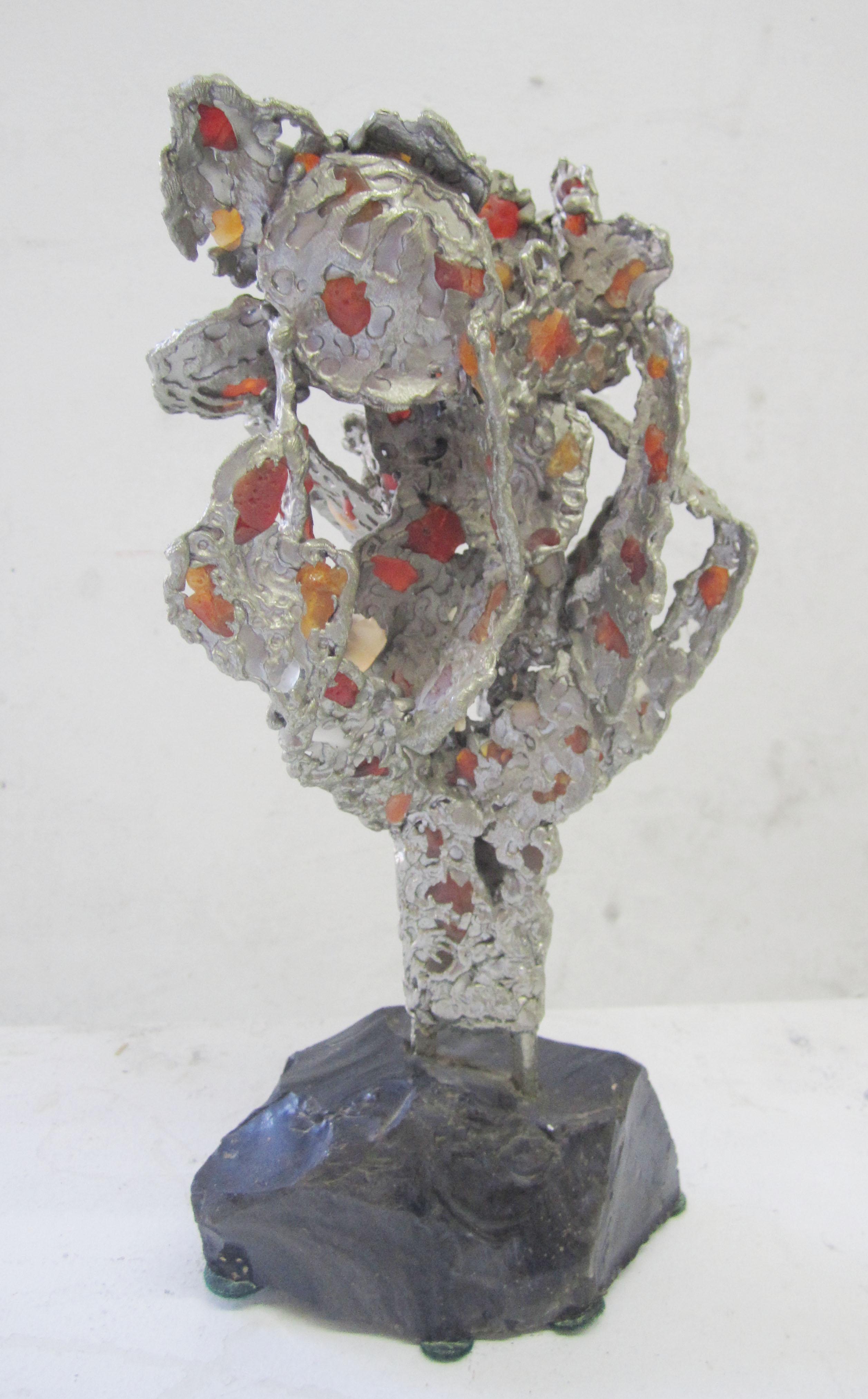 Abstract lead sculpture with agate inserts on an obsidian base.