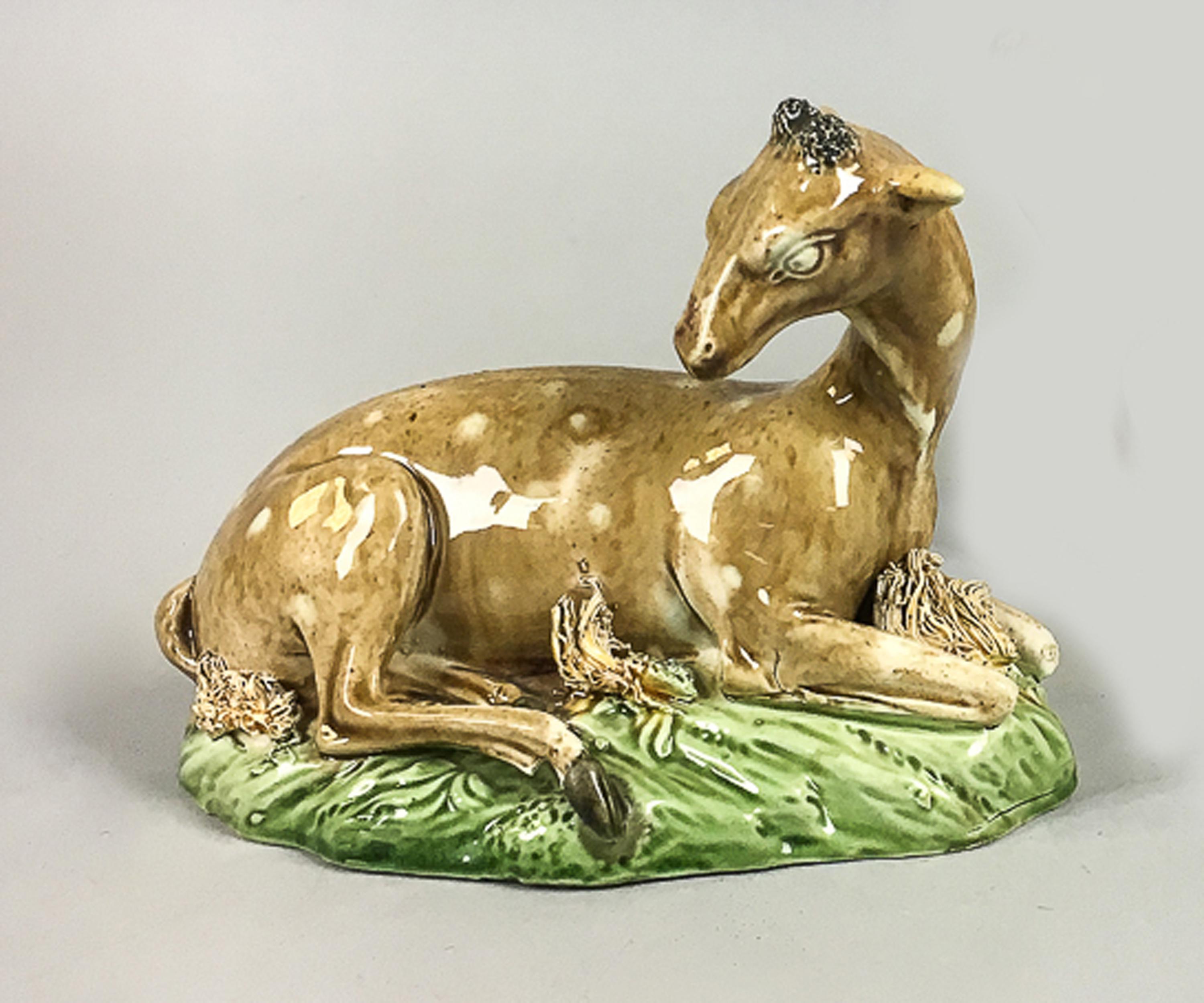 Lead-glazed earthenware model figure of A Doe, circa 1785,
Perhaps John Wood of Brownhills or Ralph & Enoch Wood of Burslem,

The pearlware figure of a hind is press-moulded and sits on a domed hollow mould with clay threads imitating grass. The