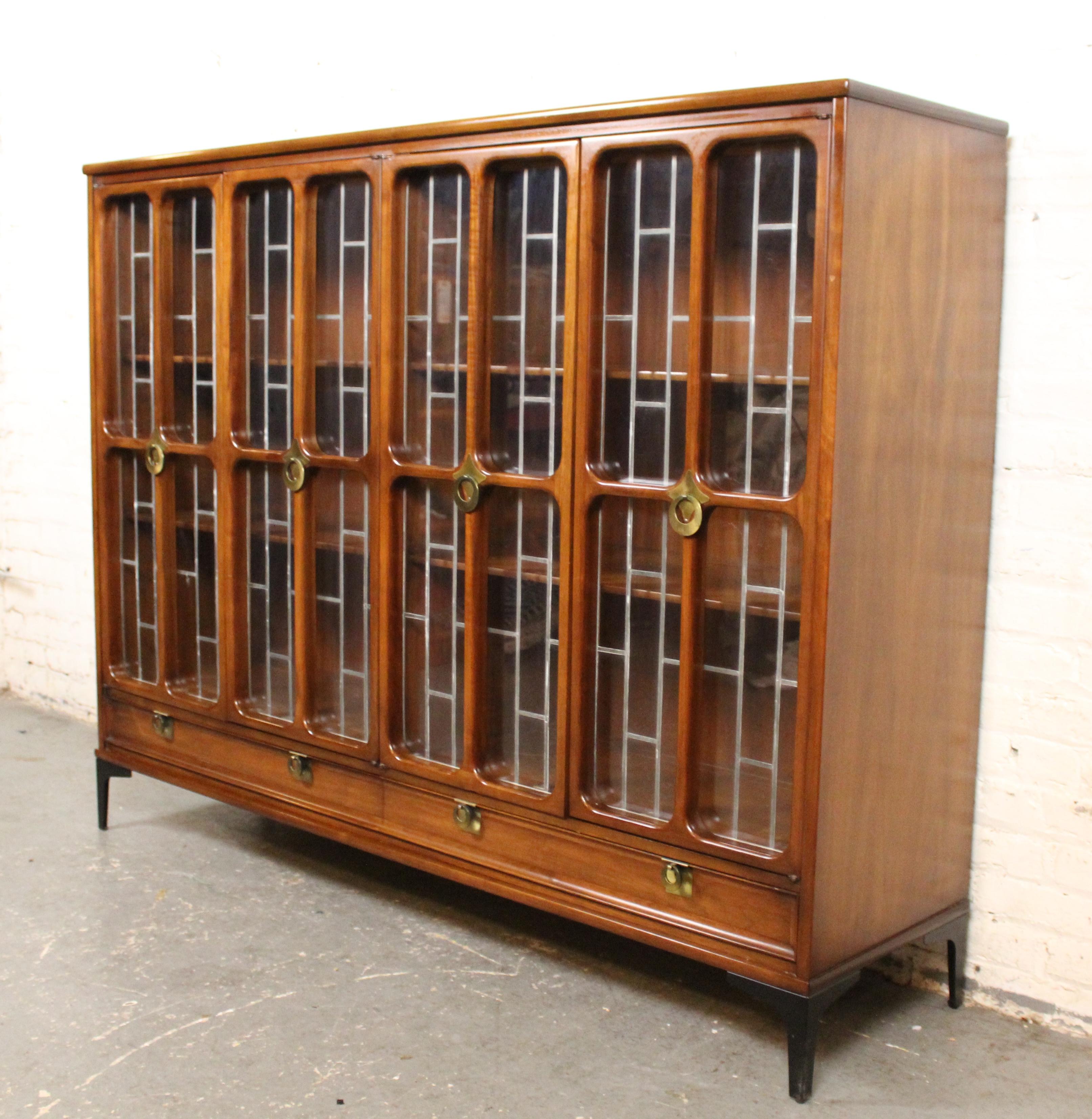 Stunning standing bookcase made by White Furniture, featuring walnut wood with leaded glass doors. Standing on metal legs with four doors and two wide drawers. Great design with solid construction and original brass hardware.
Please confirm location