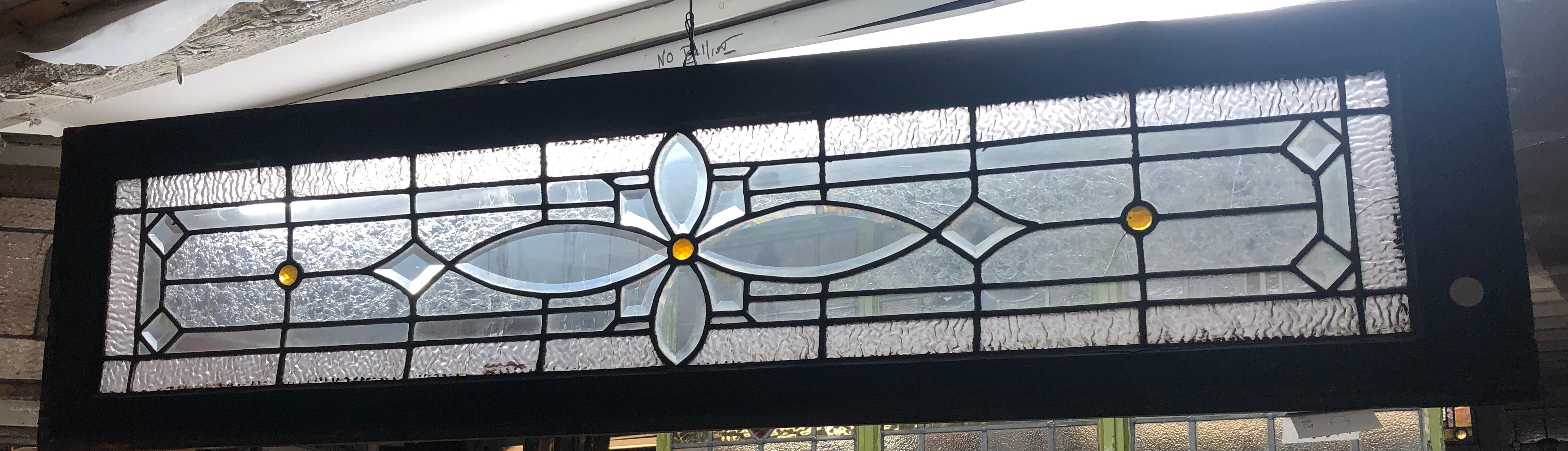 Amerikanisches Oberlichtfenster aus der Jahrhundertwende. Verbleites Design mit strukturierten Glasstücken und drei kleinen bernsteinfarbenen Kreisen.
Derzeit in einem provisorischen Holzrahmen untergebracht - die Gesamtmaße gelten für die