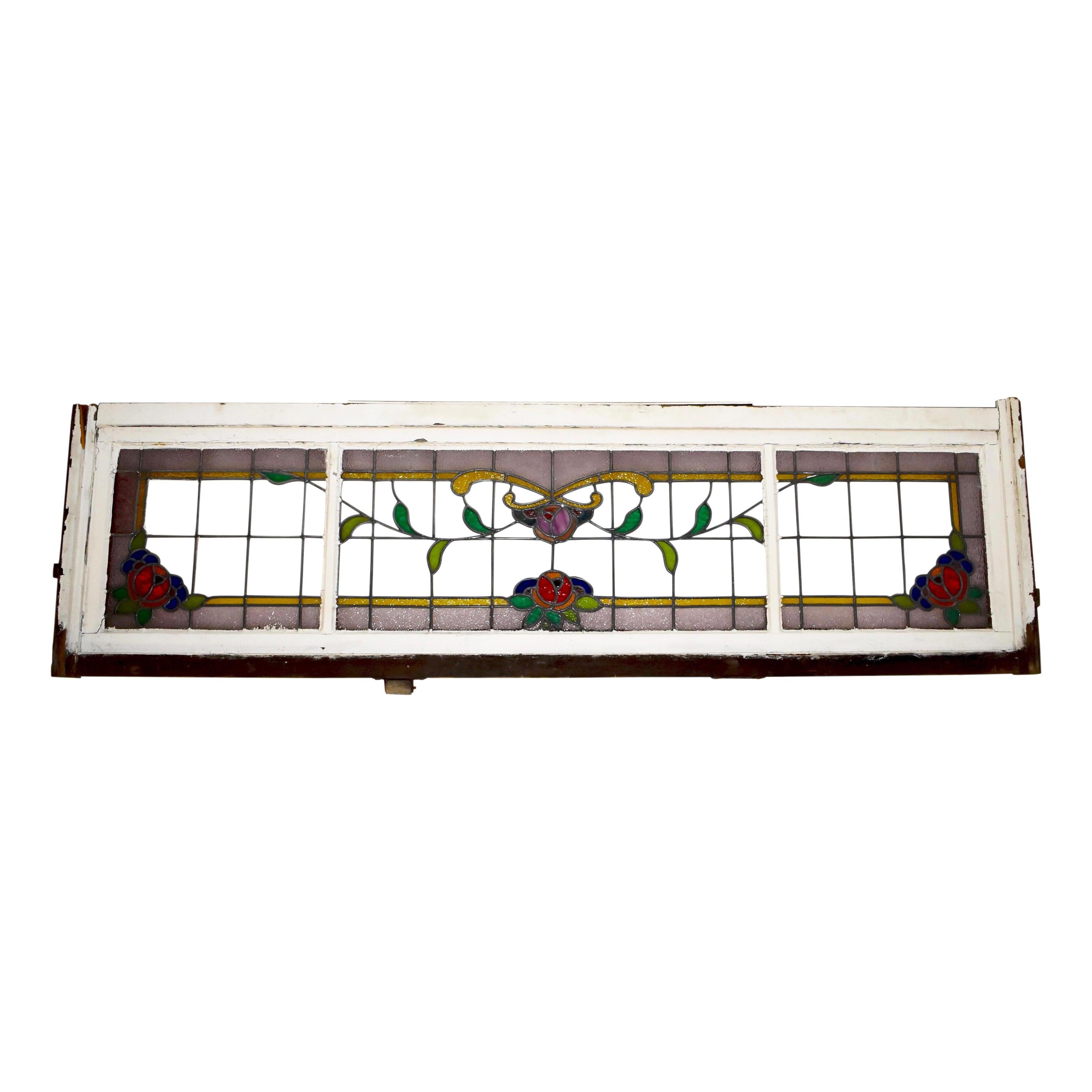 Salvaged from a building in Northern Europe, this stained glass window features a border of pink and yellow from which festooning leaves with a pink rose descend. Red roses, flanked by delicate cobalt flowers, adorn the lower corners and center.