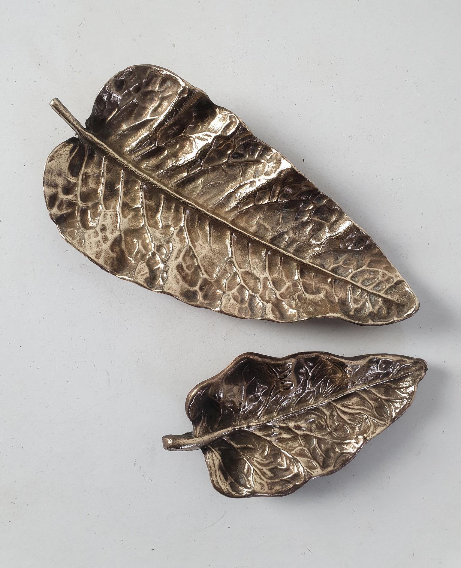 Two gold colored sand cast trays molded from a natural leaf to use for keys, nick-nacks or as ashtray. Stands on small legs.