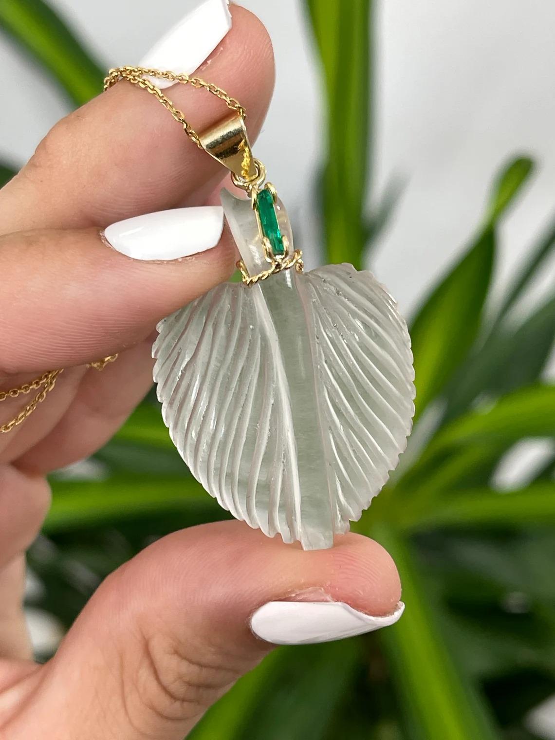 Featured is a beautiful, and captivating natural quartz and emerald pendant. White rocky quartz is skillfully-carved into a stunning leaf. A natural, fine-quality Colombian emerald rough crystal is tension set above the quartz, at the stem of the