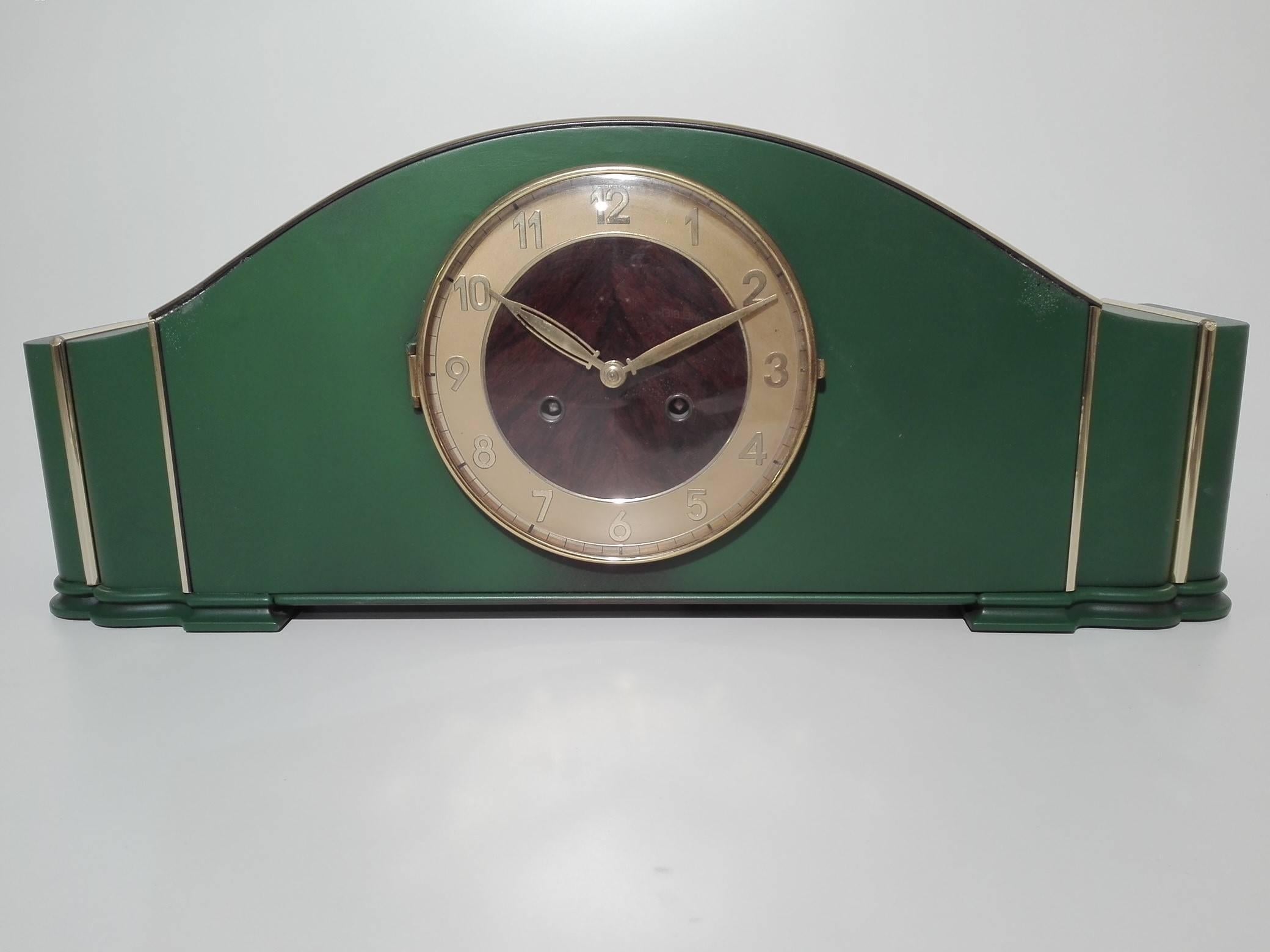 Wonderful original Art Deco desk clock or cabinet clock from the 1940s. Offers a rare, leaf green finish and fine brass applications. A stunning masterpiece with a two-toned dial made of brass and grained walnut wood. The clock is in a perfect,