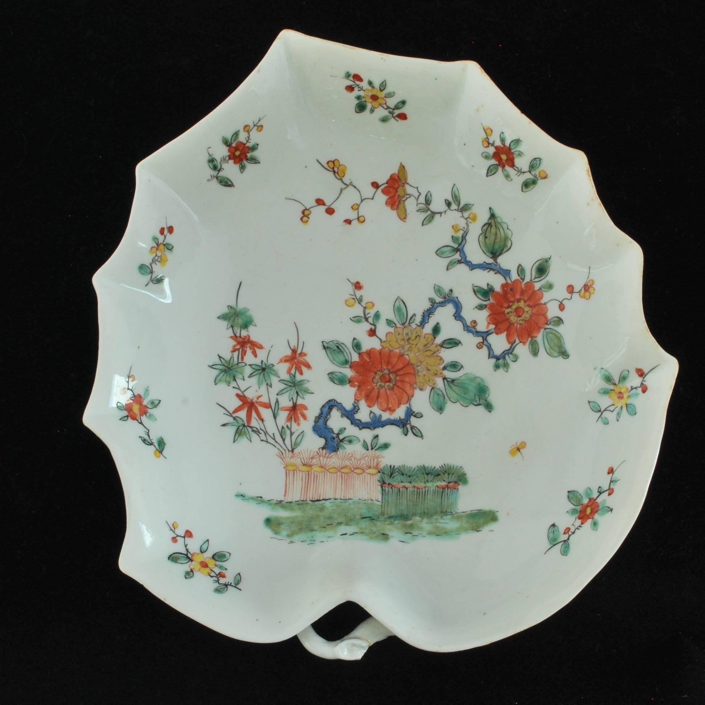 Of strawberry-leaf form with stalk handle, the underside moulded with trailing strawberry plants and with pad feet. Decorated after the Kakiemon with prunus and C issuing from banded hedges; the flowers and tiny both around the rim taken from