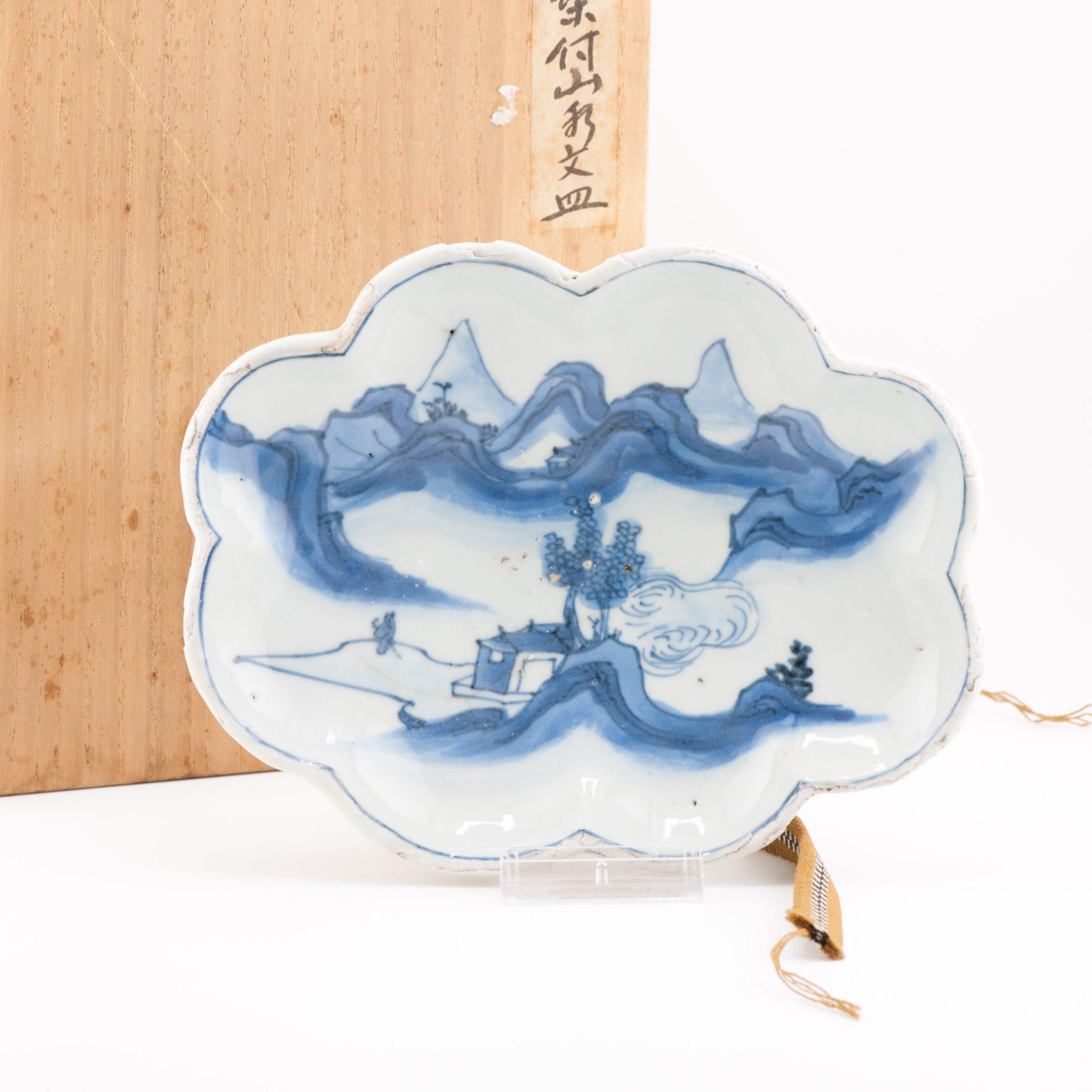 Whiting condivide con te questo bellissimo piatto da portata a forma di foglia su quattro piedi in blu e bianco.
È visibile una scena tipicamente dipinta per questo periodo. Paesaggio montano con una casa al centro e una figura in viaggio. È in vaso