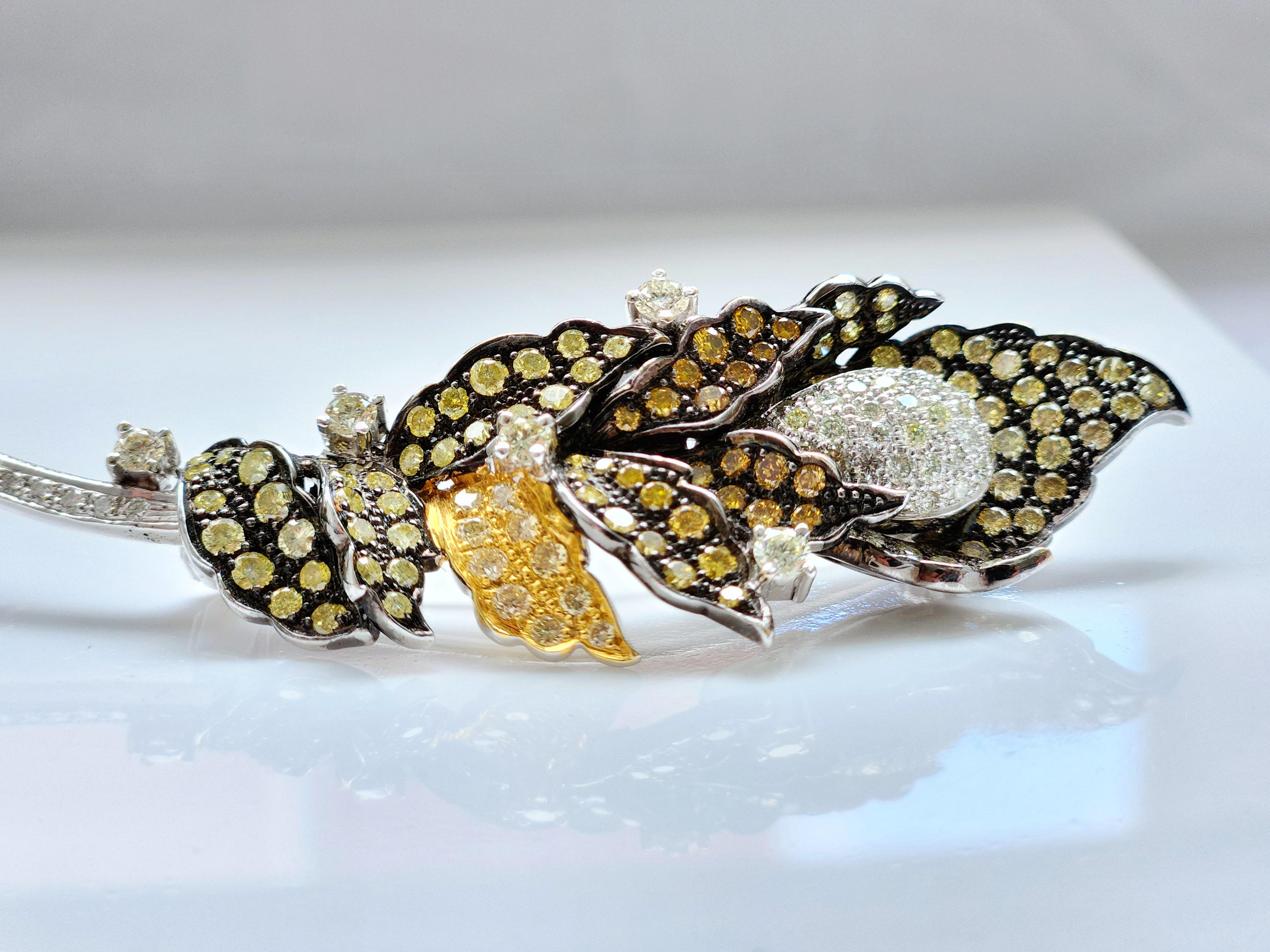 The Leaf Shaped Multicolor Diamond Brooch is a dazzling piece of jewelry that showcases exquisite craftsmanship and breathtaking beauty. Featuring a seed of white melee diamonds at center which is surrounded by delicate petals of greenish yellow and