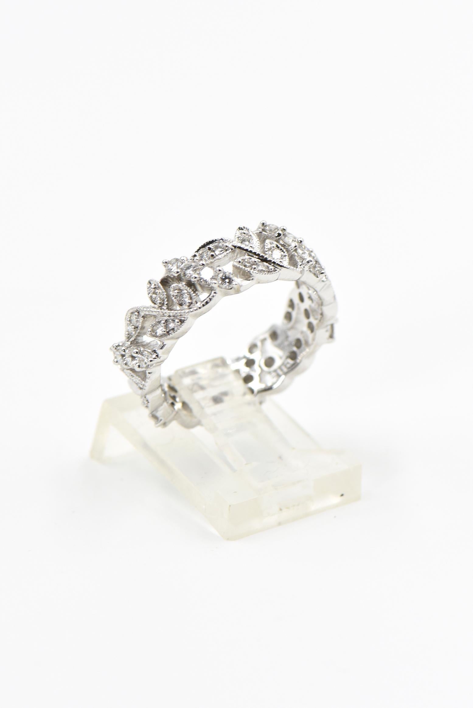 Beautiful 18k white gold eternity band featuring a vine with four leaves design alternating between a diagonal line of four prong set diamonds.  
The band is 6.43 mm wide. 
It is a US size 7.