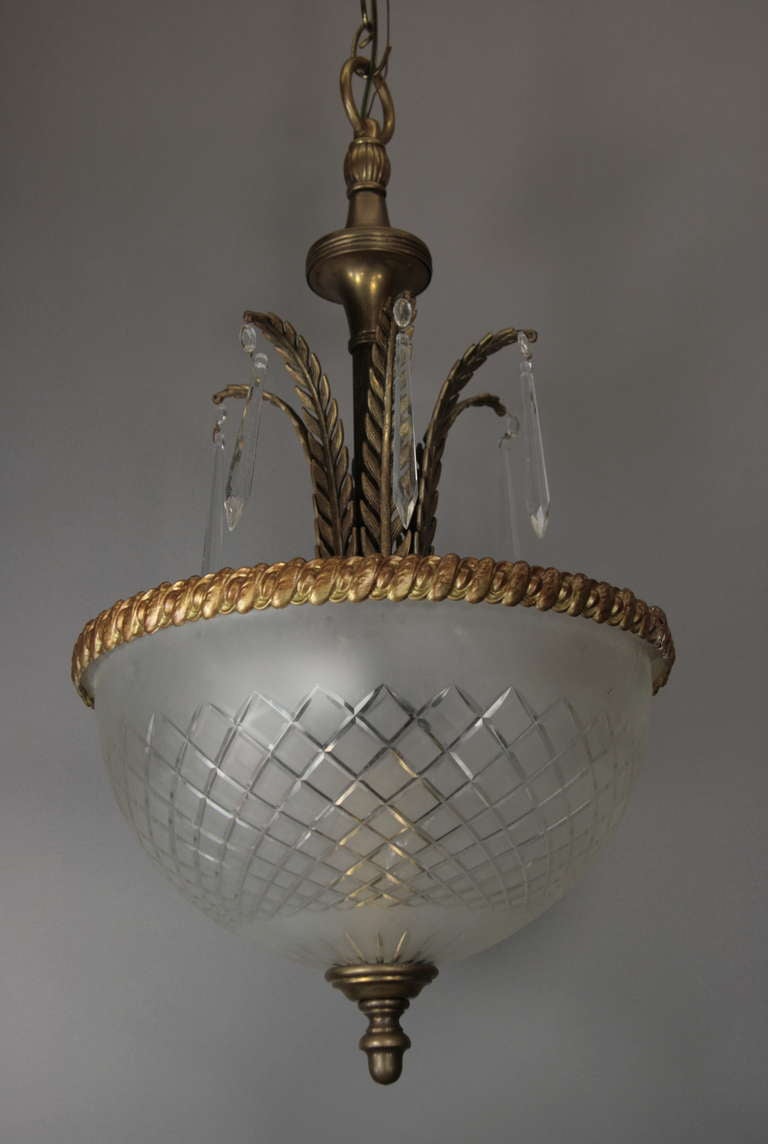 A wheel cut satin glass dome set in a darkened brass leafy stem ending with crystals prisms. Three internal light.