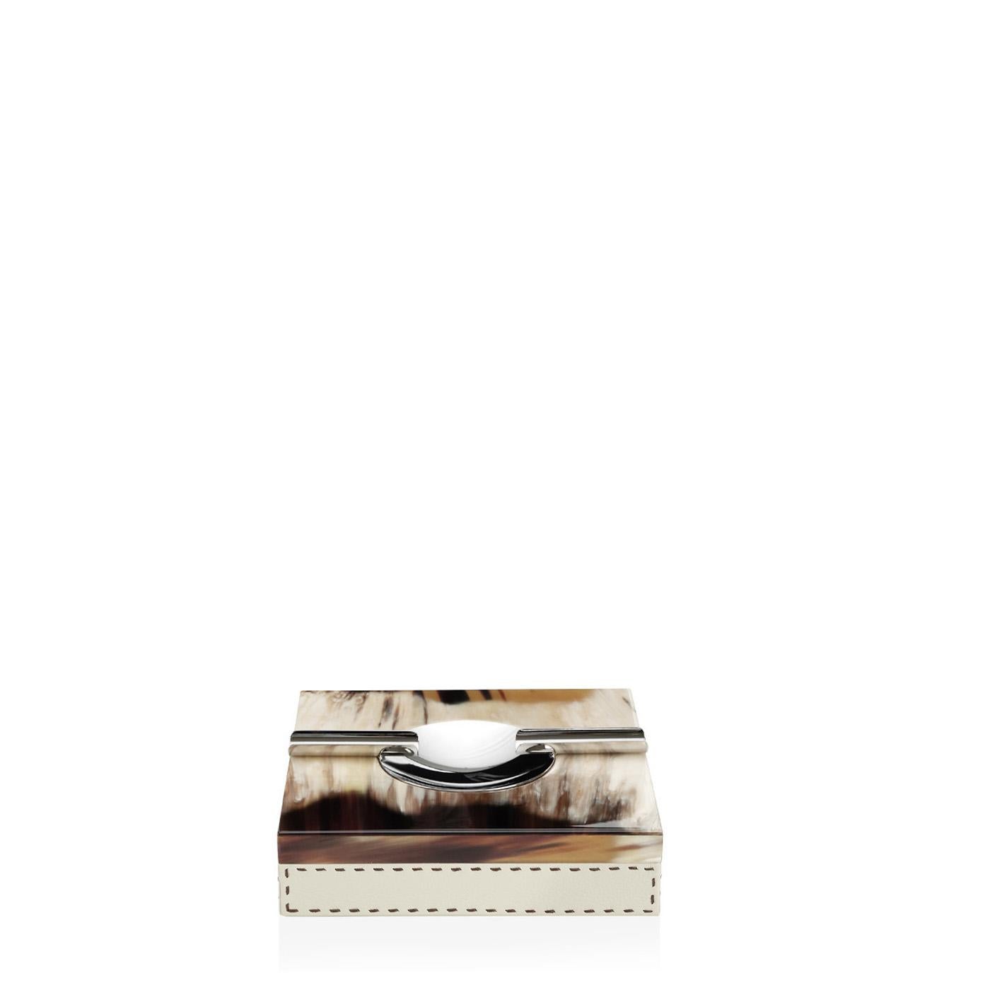 Our Leandro ash tray is an essential for cigar connoisseurs as well as a refined decor element. The ash tray is generous in dimensions and is upholstered in Aida pebbled leather, Ice-cream colour. The piece is graced by elegant inlays in Corno