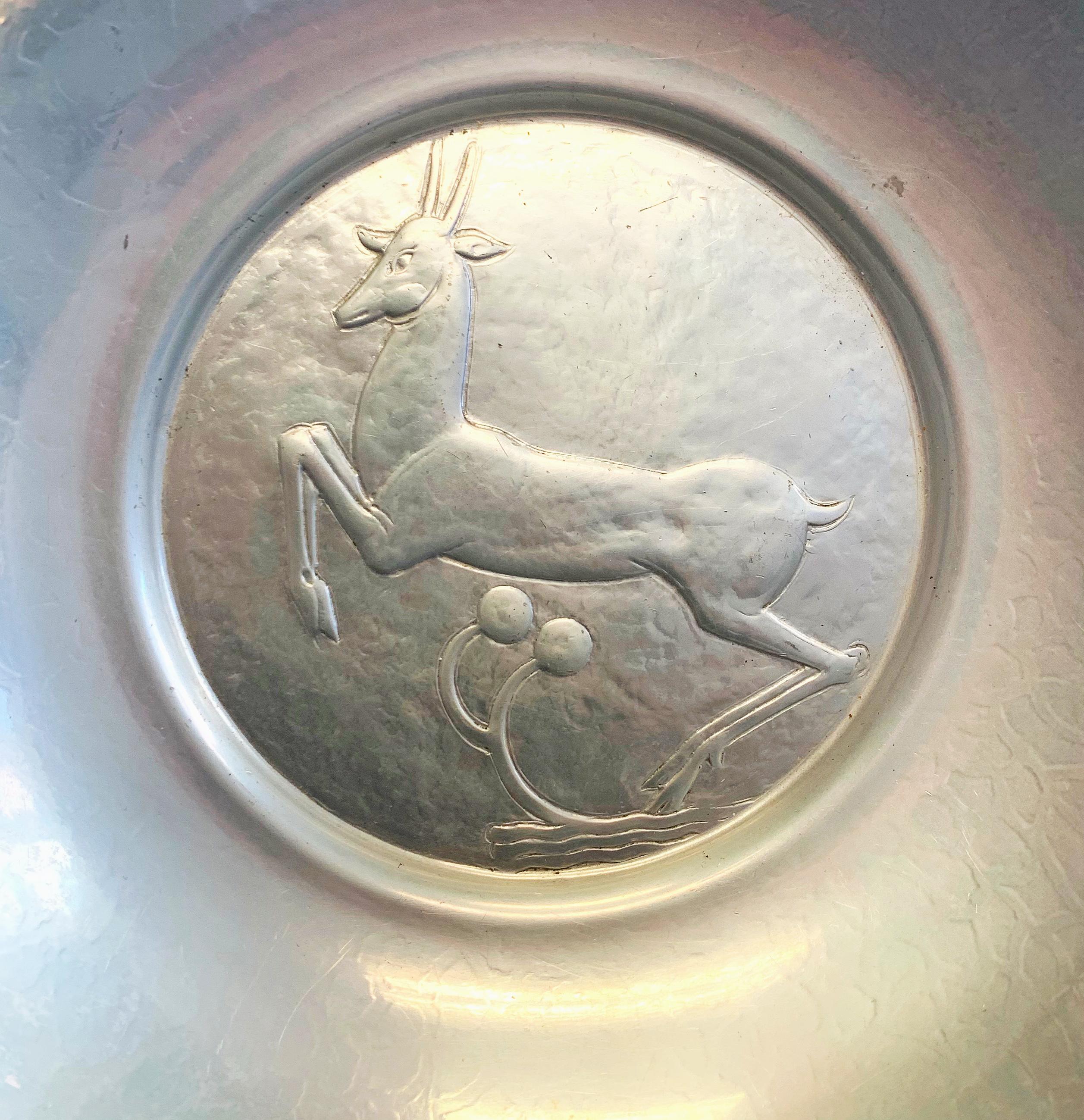 One of the most iconic, though rare, pieces ever made by Oscar Bach, this bowl features an iconic leaping stag in high Art Deco style, executed in a silvery aluminum finished in a subtly iridescent glaze. This bowl, and a series of rare chargers in