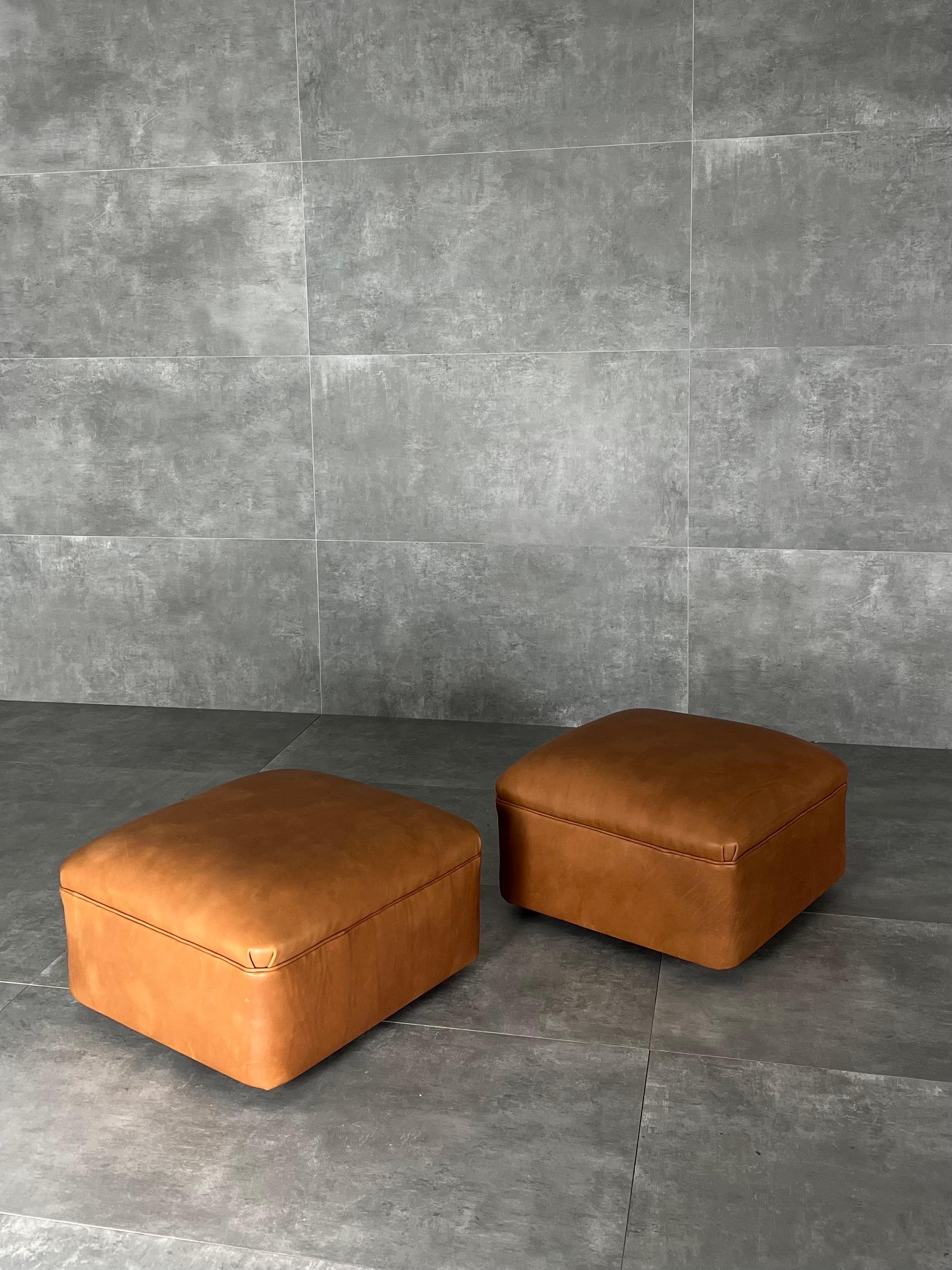 1960s ottomans with squared shape. They features a new cognac leather reupholster and small wheels on the base which give stability while used.