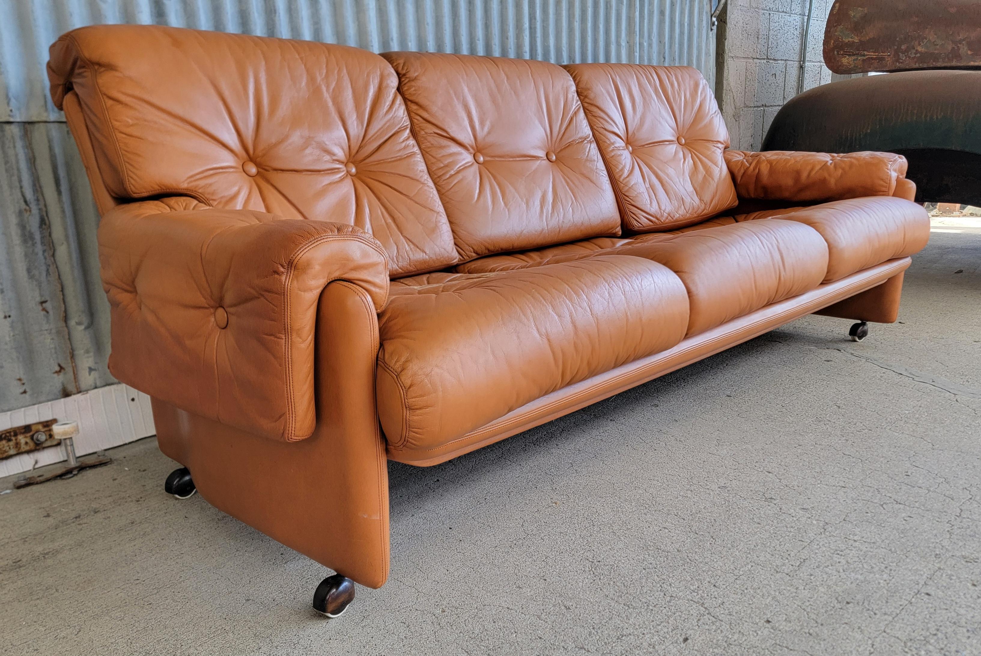Cognac leather 3 seat sofa attributed to Tobia Scarpa. Removable cushions with metal snaps to secure in position. Castors for ease of moving. Comfortable and classic! 

80 inches wide.
31.25 inches high.
34 inches deep.
Seat height 17.5 inches.