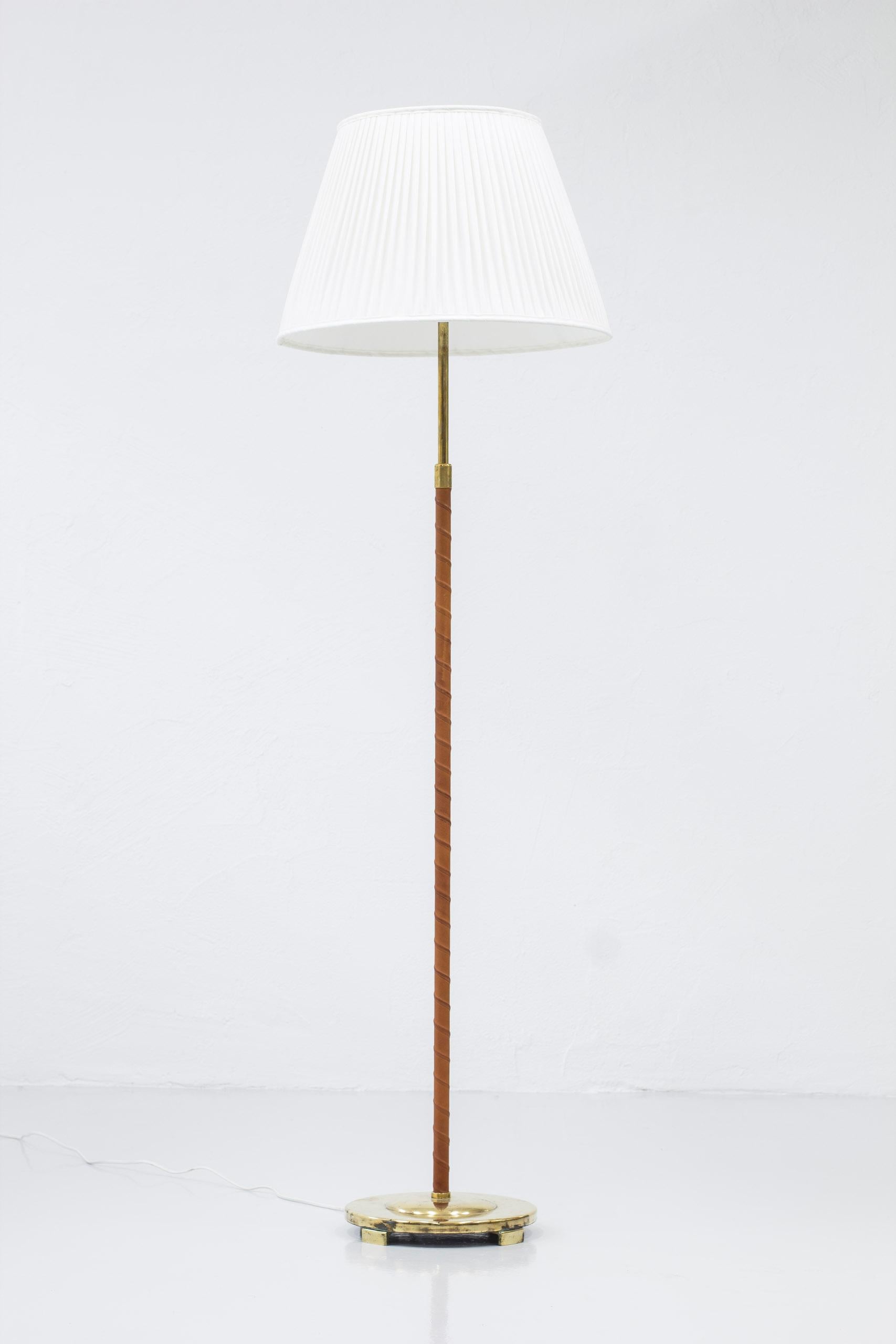 Floor lamp model 32753 produced by Nordiska Kompaniet. Attributed to the head designer for the NK lighting department Bertil Brisborg. Produced around the 1940s. Made from brass, lacquered metal and leather. The shade is redone after the original