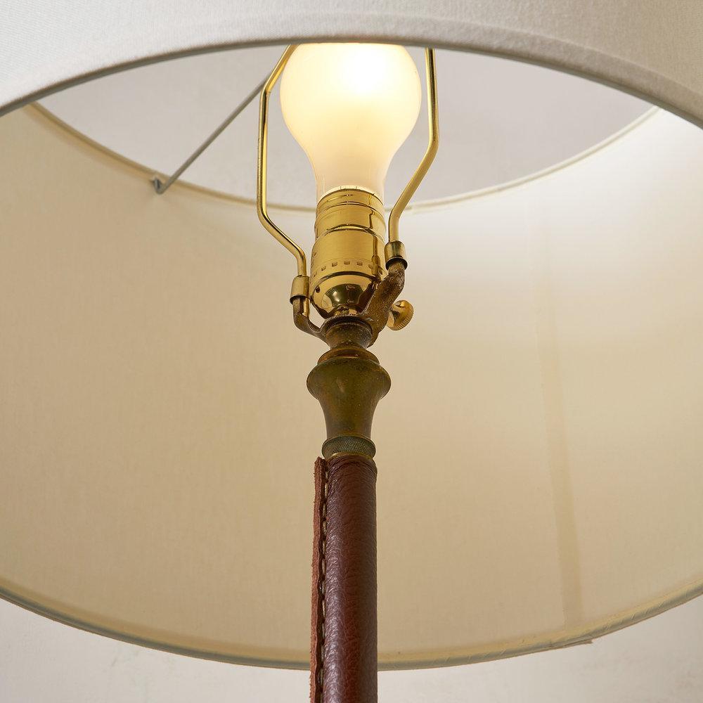 A handsome floor lamp in handstitched cognac leather on a brass tripod base. Similar to styles by Kalmar and Gino Sarfatti. 

Sourced in France. 

Newly rewired for U.S use. Accepts standard base bulb up to 60 watts. 

Lampshade not included.