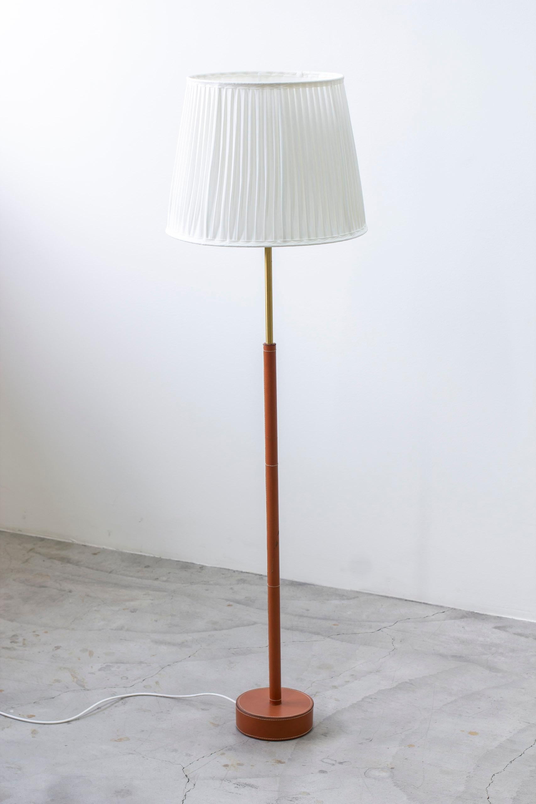 Floor lamp model G08 produced by Bergboms. Made in Sweden during the 1950s. Leather wrapped base and stem with white stitching. Brass details and fitted with a new hand sewn lamp shade in off white with single pleating. Good vintage condition with