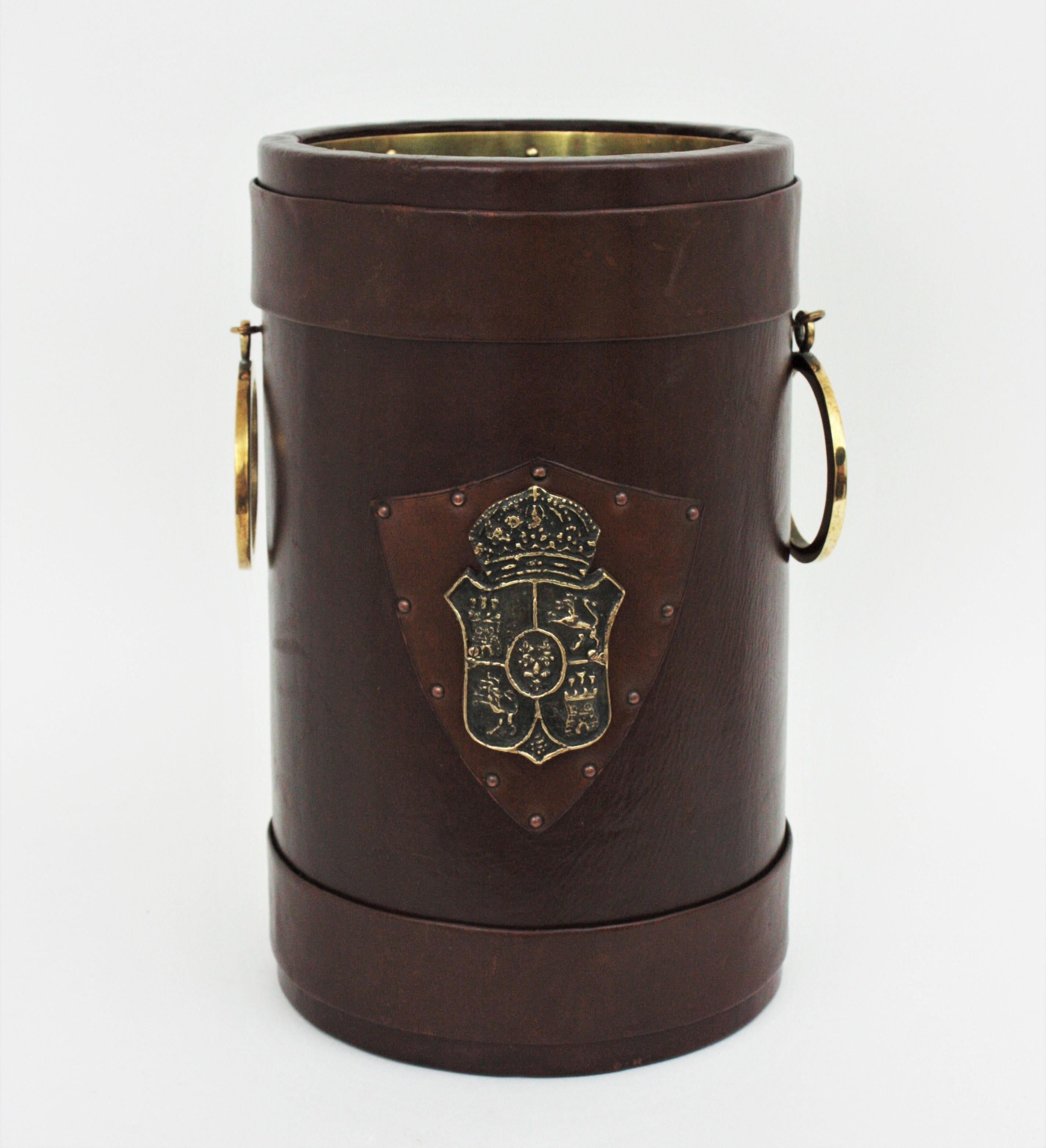 Umbrella stand or waste basket bin with handles and decorative coat of arms, leather, wood, brass. Spain, 1960s
This leather, metal and wood wastebasket from Spain has a beautiful design with brass handles both sides and the spanish coat of arms at