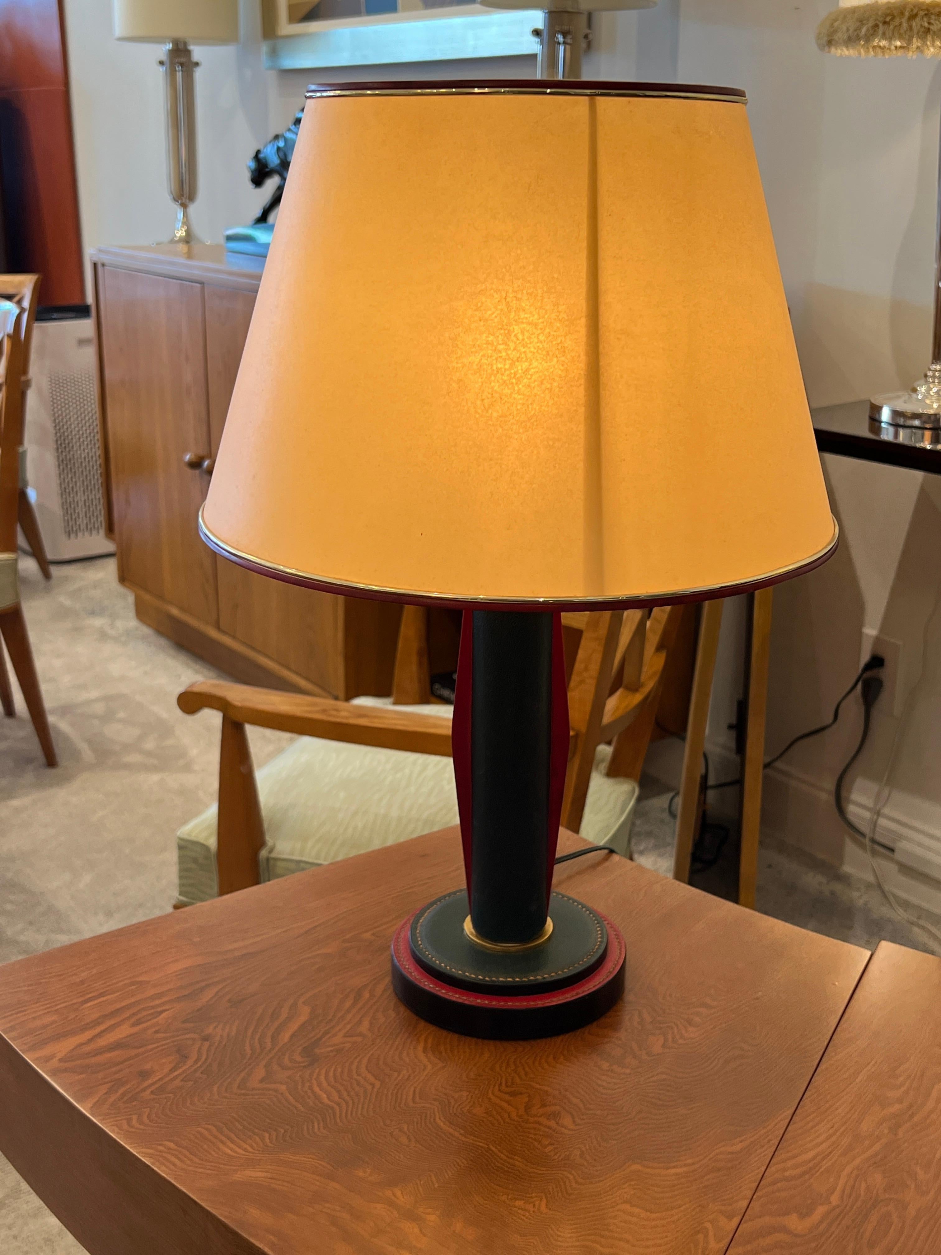 Art Deco Tischlampe mit einem Schaft aus Leder in Hermés Forest Green mit roten Lederdetails an der Seite des Schaftes und des Sockels. Dieses Stück wird mit einem Lampenschirm aus Papier geliefert.
