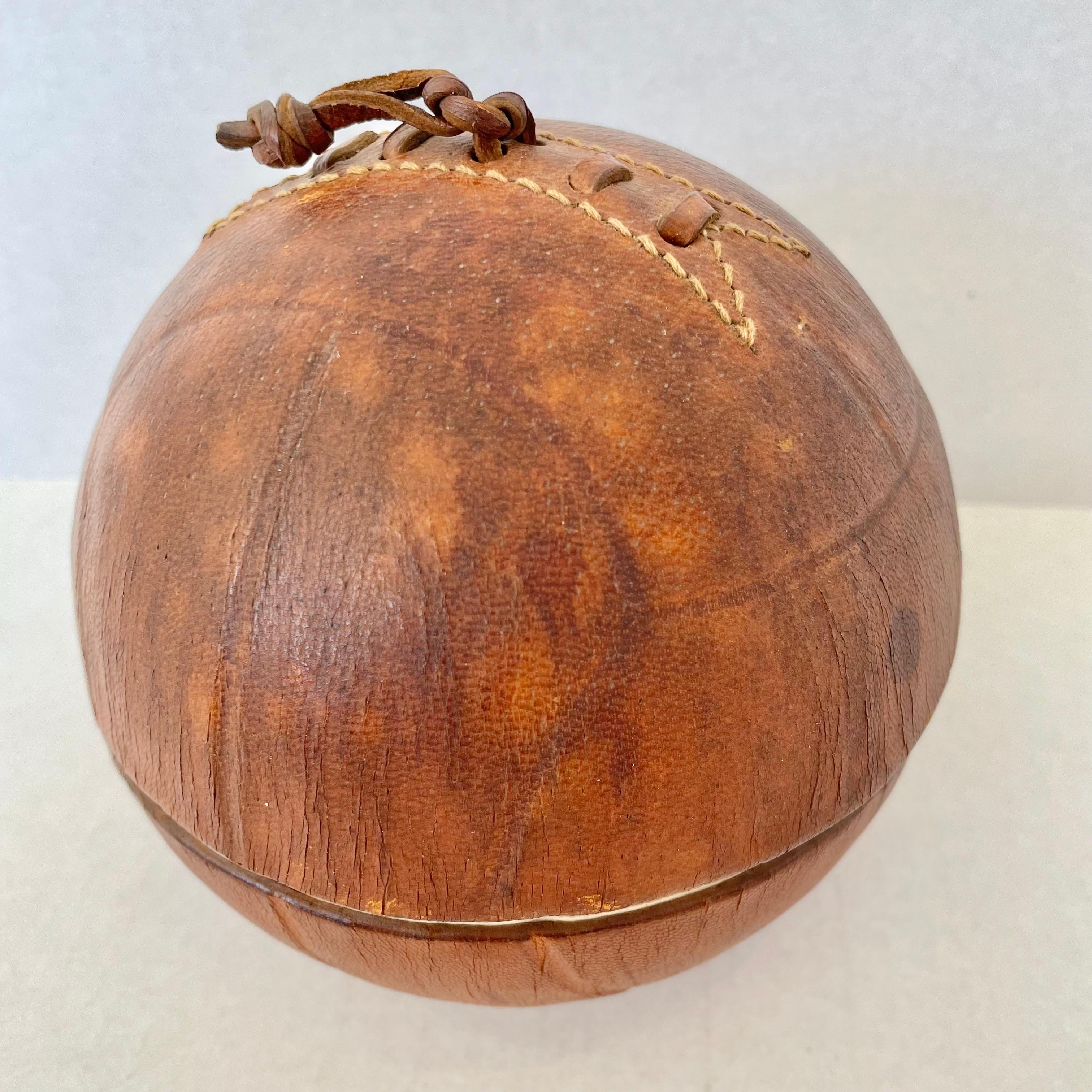 Handsome leather and ceramic ashtray/catchall by Longchamp in the design of an old soccer ball. Stamped with Lonchamp - France and logo. Beautiful patina to brown leather. Opens up to reveal the ashtray and another compartment that could be used as