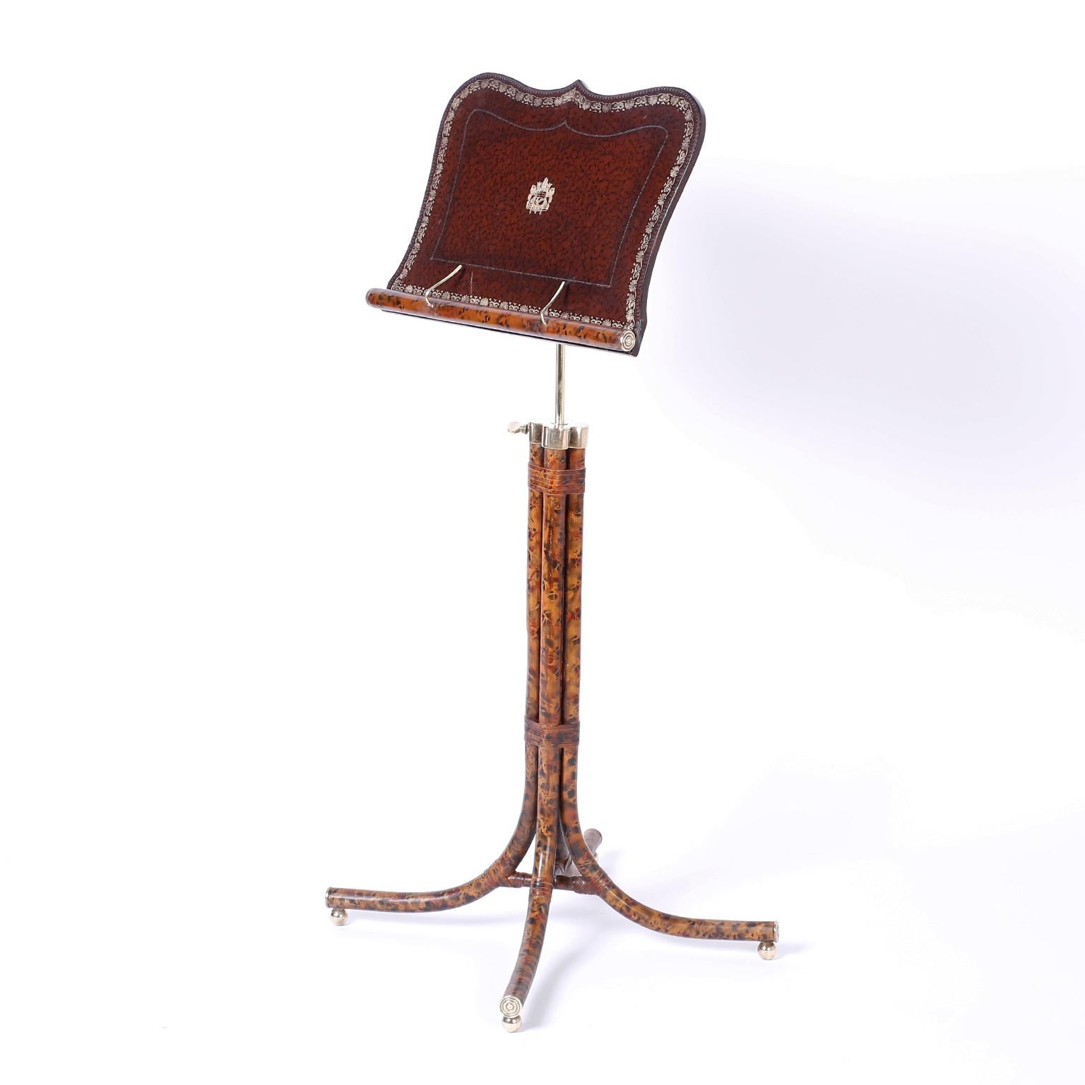 Music stand or lectern featuring a tooled leather tray, brass hardware with adjustable height, and a four legged faux tortoise metal base on ball feet. Probably Maitland-Smith. 

Height ranges from 45 inches to 53 inches.