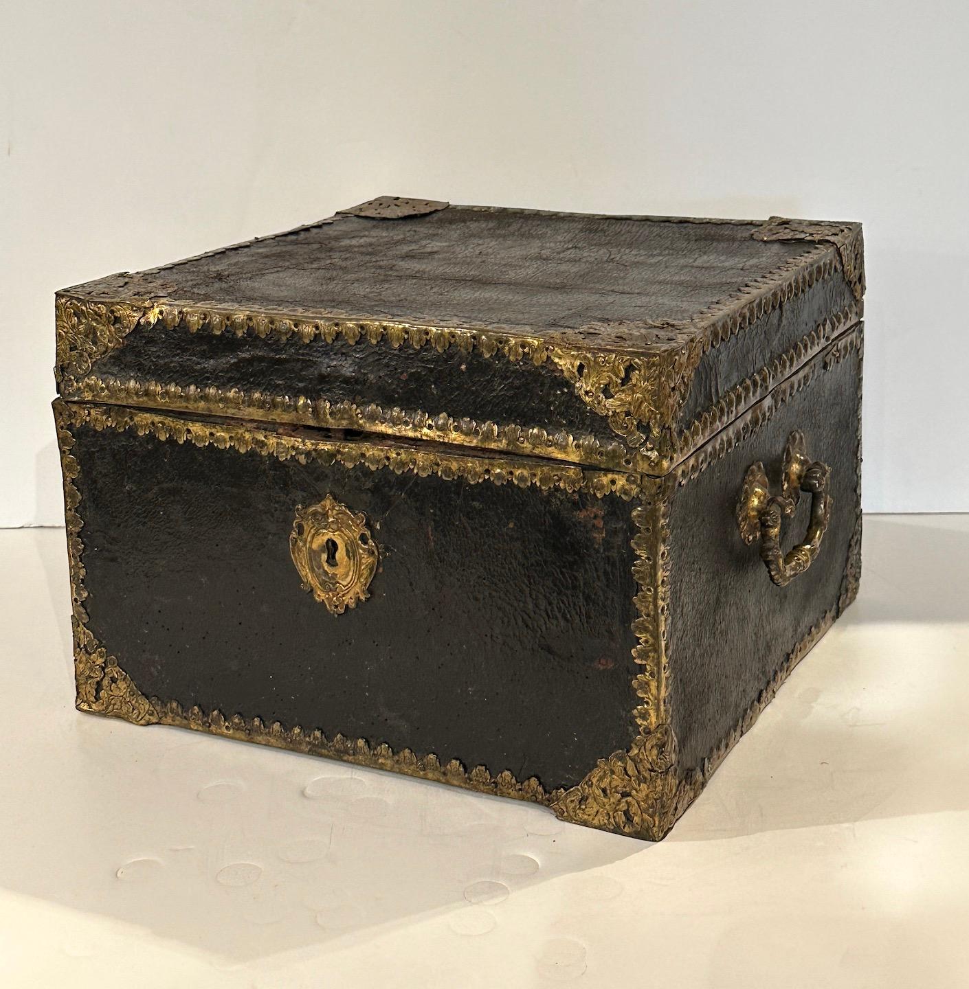 Leather and incised brass trimmed document box lined in paisley paper.  Brass handles.