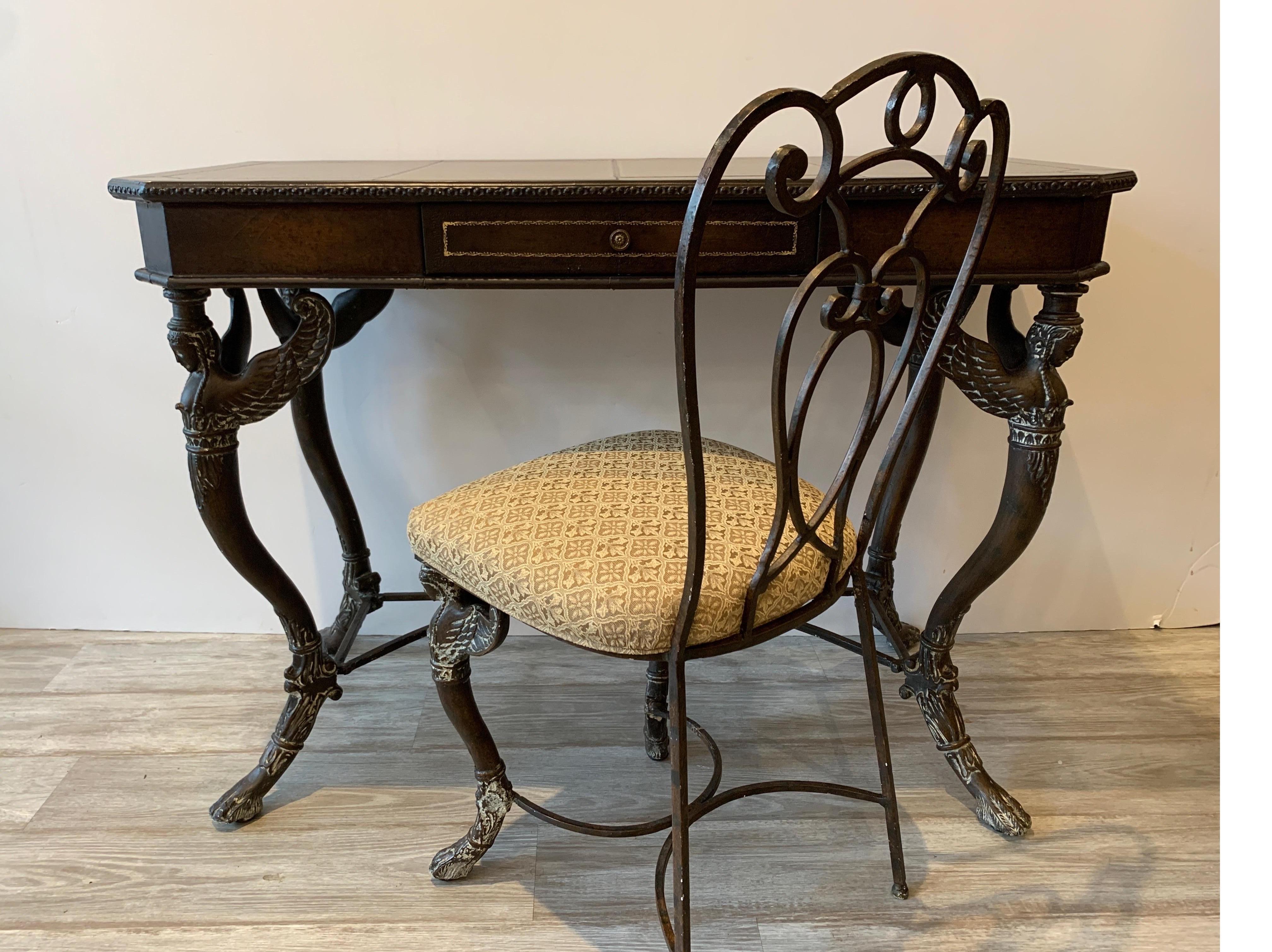 Continental leather and bronze finished metal console writing table with matching chair. The leather covered surface with center drawer resting on four legs with winged caryatid figures. In the manner of Maitland Smith. The chair is 16 inches wide,
