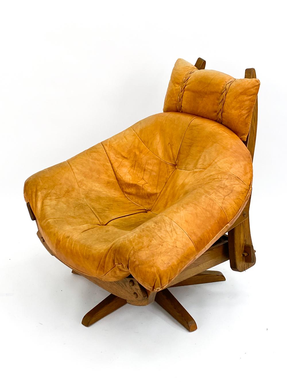 Feast your eyes upon this handsome mid-century swivel lounge chair with cognac leather cushions. Designed in a manner evocative of Gerard Van den Berg, this chair has an incredibly unique appearance that is sure to catch the eye of guests. With