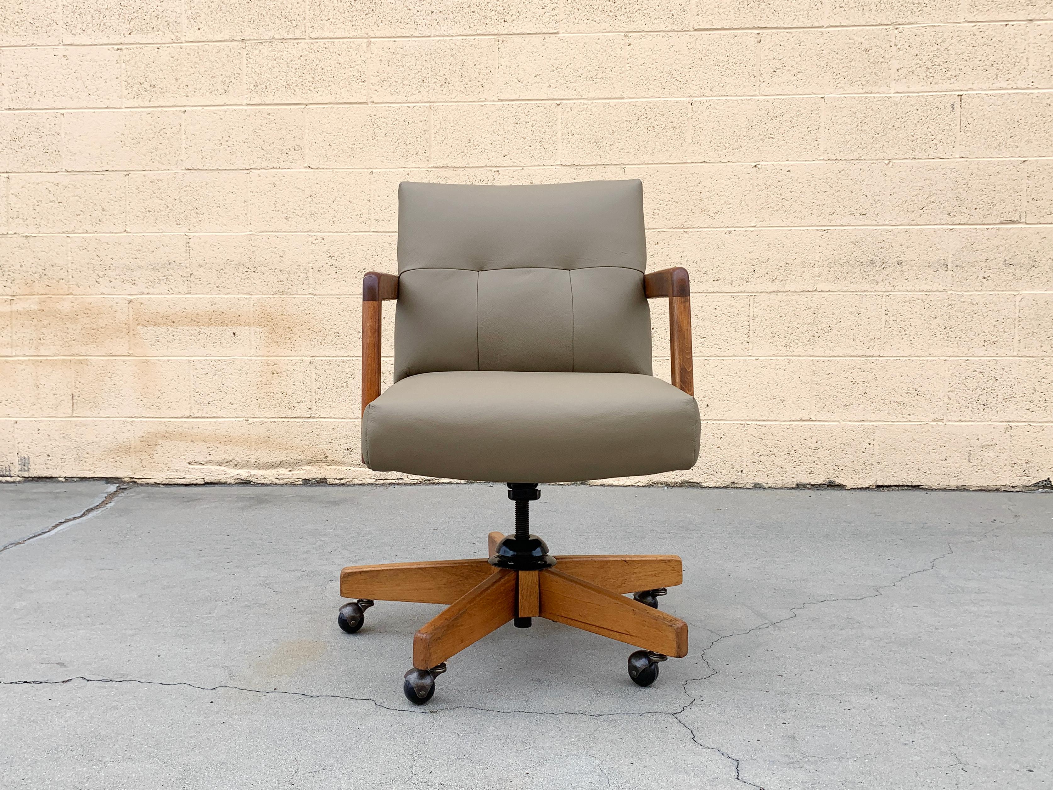 Handsome 1970s office chair by Gordon Manufacturing Co. Newly reupholstered seat in quality grey leather; reconditioned oak frame and base. Swivels and tilts. In excellent vintage condition. 

Dimensions: 
Base– 26