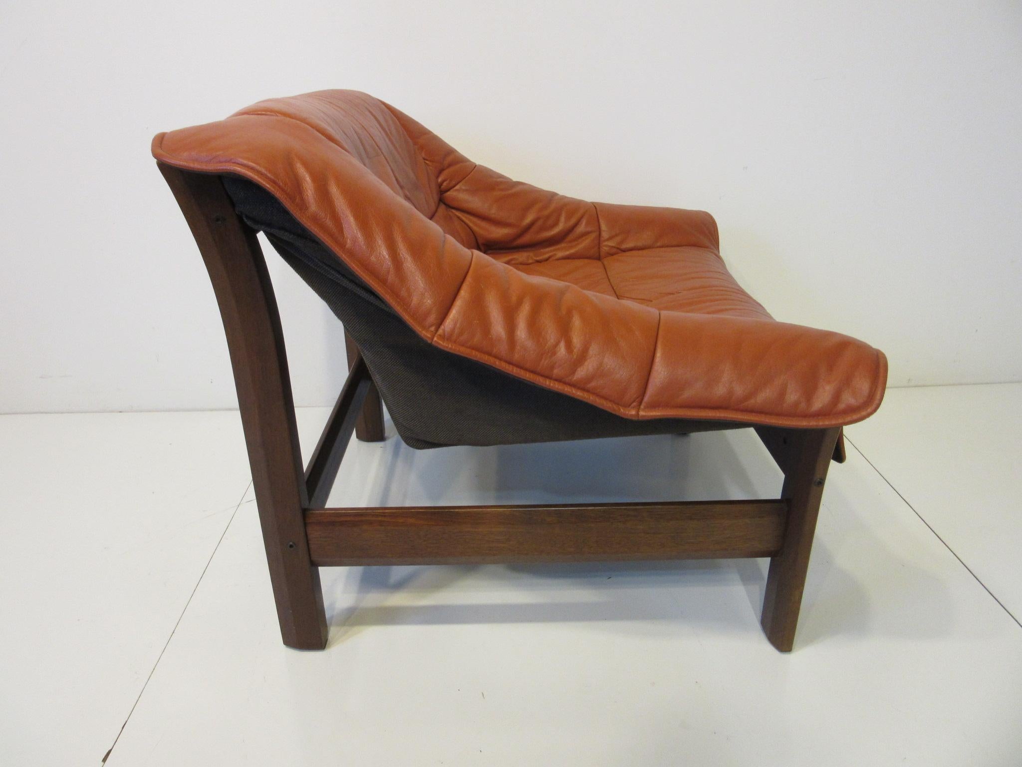 A leather covered lounge chair with a Jacaranda rosewood frame designed in the manner of Percival Lafer with comfort and style in mind. Made in Brazil the designers and crafts people who made these midcentury and modern pieces are finally getting