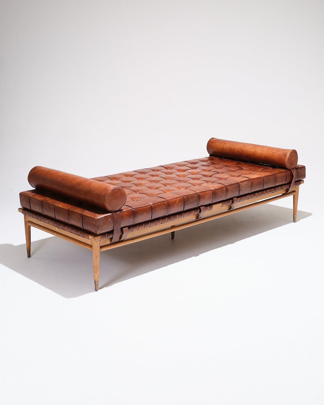 Lit de jour emblématique de l'école belge, conçu par Olivier de Schrijver pour Design/One dans les années 1970.
Structure en bois massif avec un sommier en cuir tressé et un matelas fixé par des sangles. Assise et dossier en cuir marron tufté