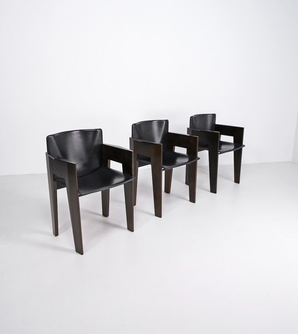 Black leather and stained wooden dining chairs designed by Dutch designer Arnold Merckx and produced by Arco in the 1980s. 

Arnold Merckx graduated from the Academy of Visual Arts and Technical Sciences in Rotterdam, after which he founded his