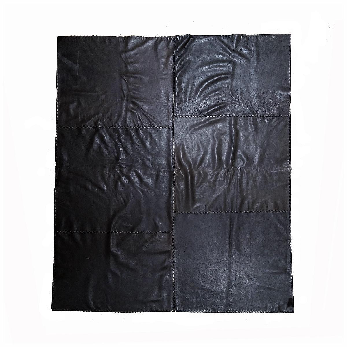A leather and wool blanket or throw, handcrafted in New Mexico around 2015. 

Supple, soft and flexible deer hide patches in black / ebony brown, beautifully sewn together quilt-style, on a whole piece of gray virgin wool. Its thickness, softness