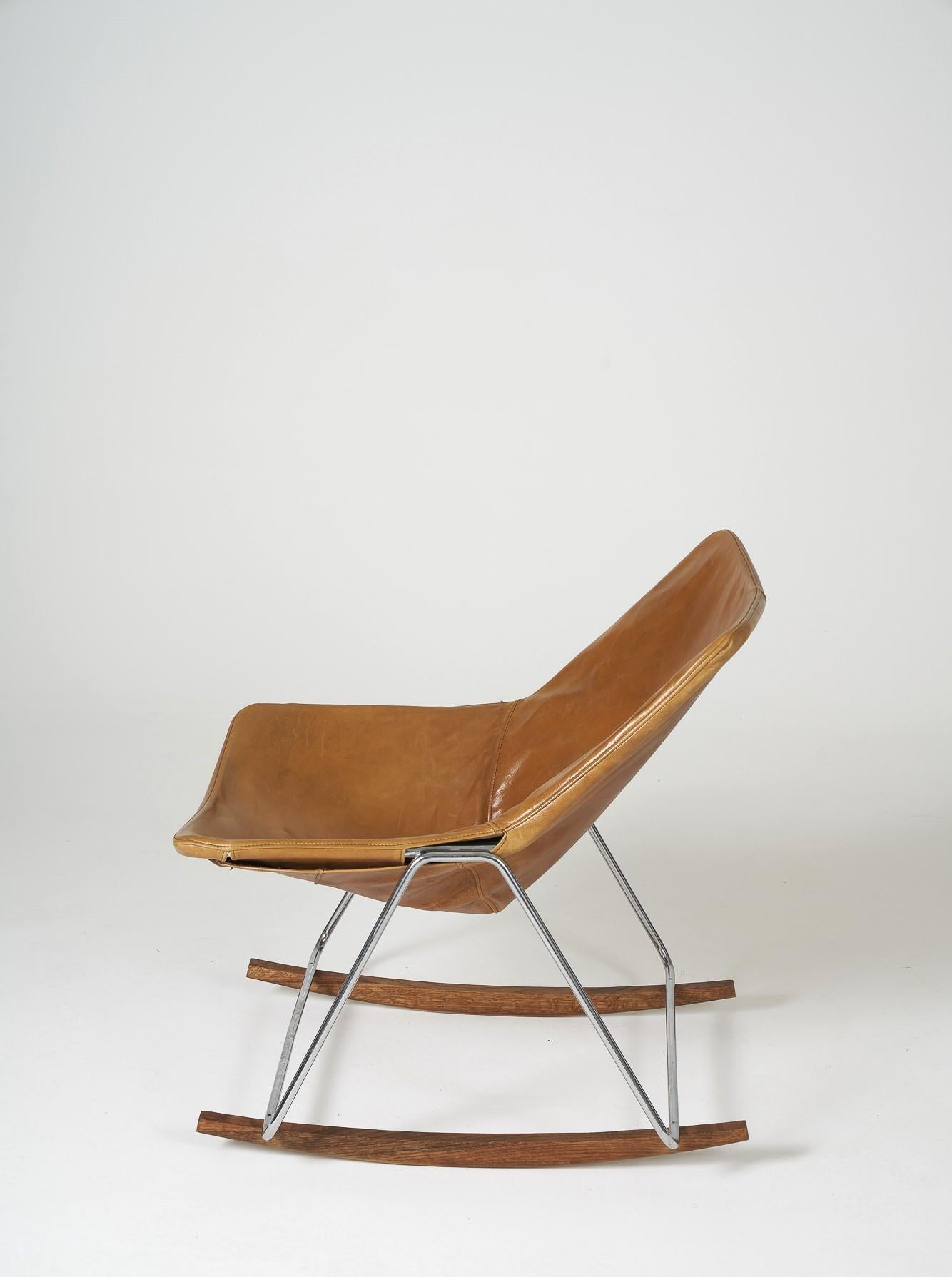Rocking chair G1 designed by Pierre Guariche in the 50s. Seat in cognac leather, structure in chromed steel and legs in solid oak. Reissue in very good condition.