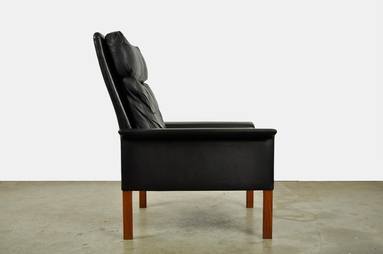 Classic vintage armchair (high model) designed by Hans Olsen and produced by CS Møbler Glostrup, 1960s. Beautiful black leather men’s armchair standing on square teak wooden legs. The armchair has a loose leather back, head and seat cushion, where