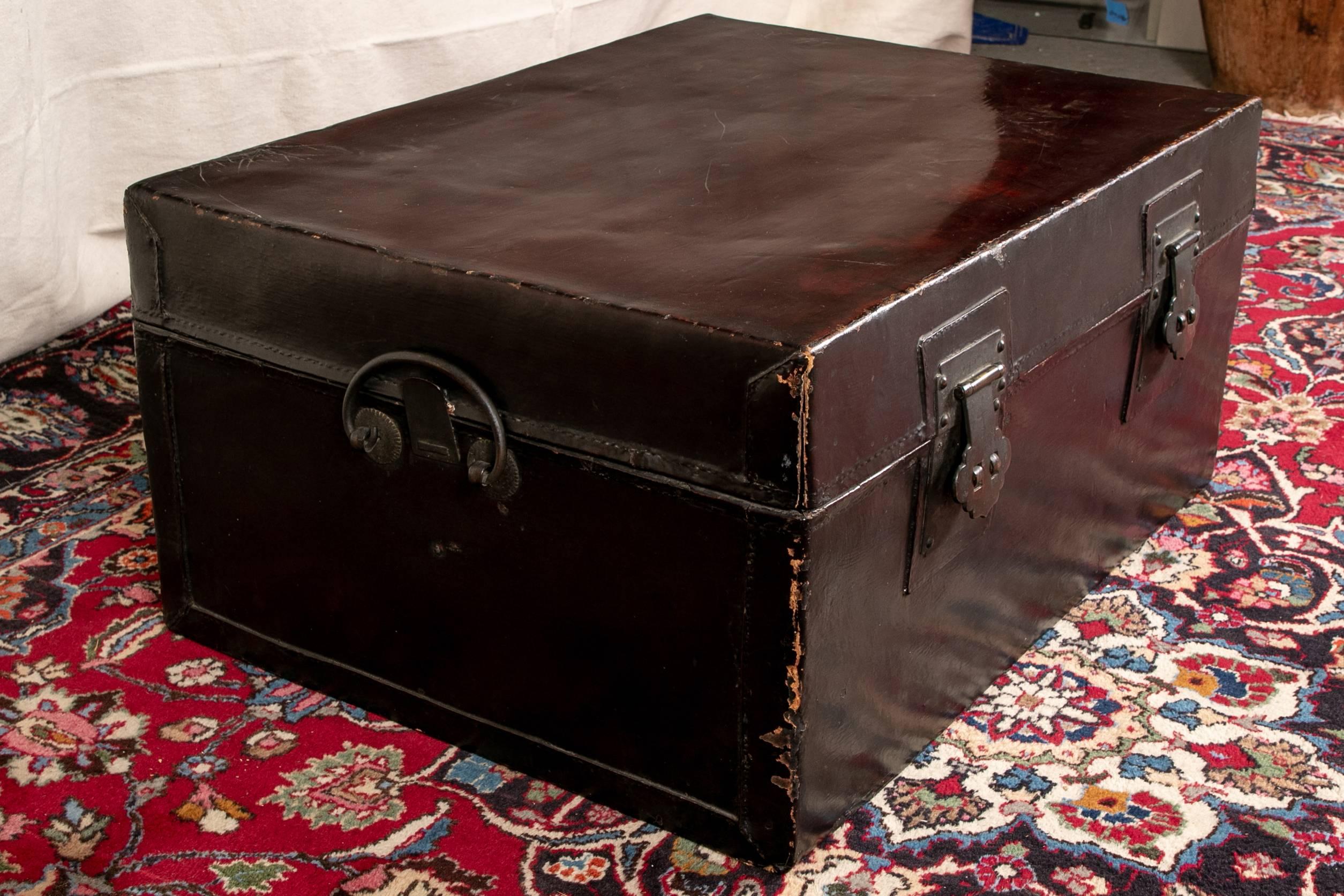 Asian trunk as coffee table, lacquer and Pig skin  in black with an oxblood tone top, nice vintage patina, with iron hinges, locks (lacking the pins), and side carry handles. 

Condition: Expected wear and signs of use including worn top.