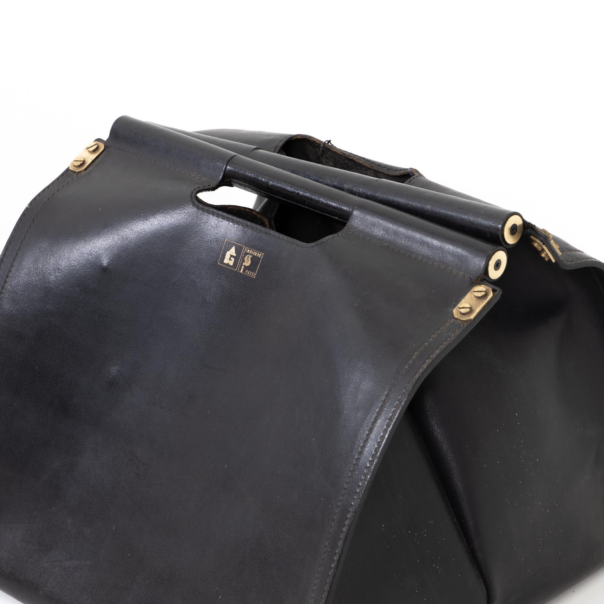Large bag made of black leather with brass fittings. This leather bag was designed for stylish storage for logs by Afra and Tobia Scarpa for the Italian fireplace manufacturer Dimensione Fuoco Bellona in the 1980s. Below the handle is the company's