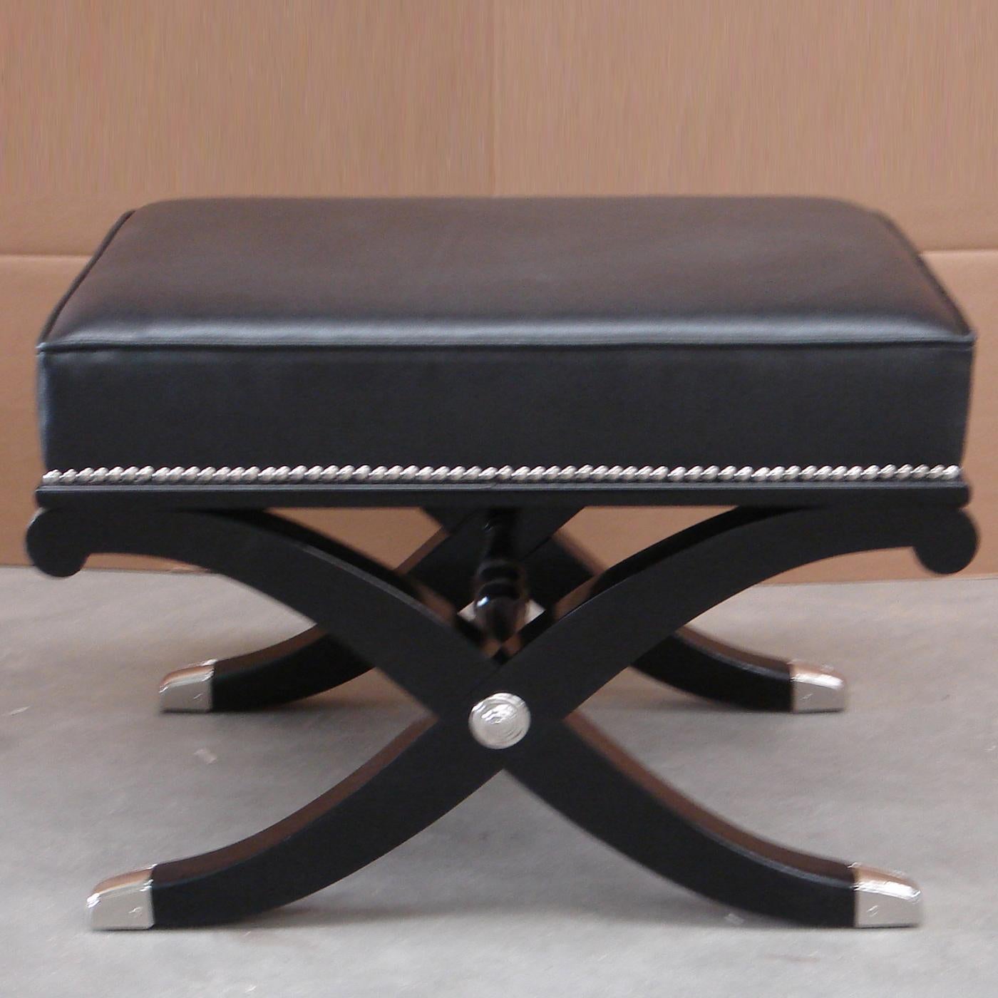 This stunning bench boasts a solid wood base with a glossy black finish, enhanced with polished chrome metal accents. Its padded seat is upholstered in soft tonal leather, detailed with a raised trim for a refined touch. Adorned with studded
