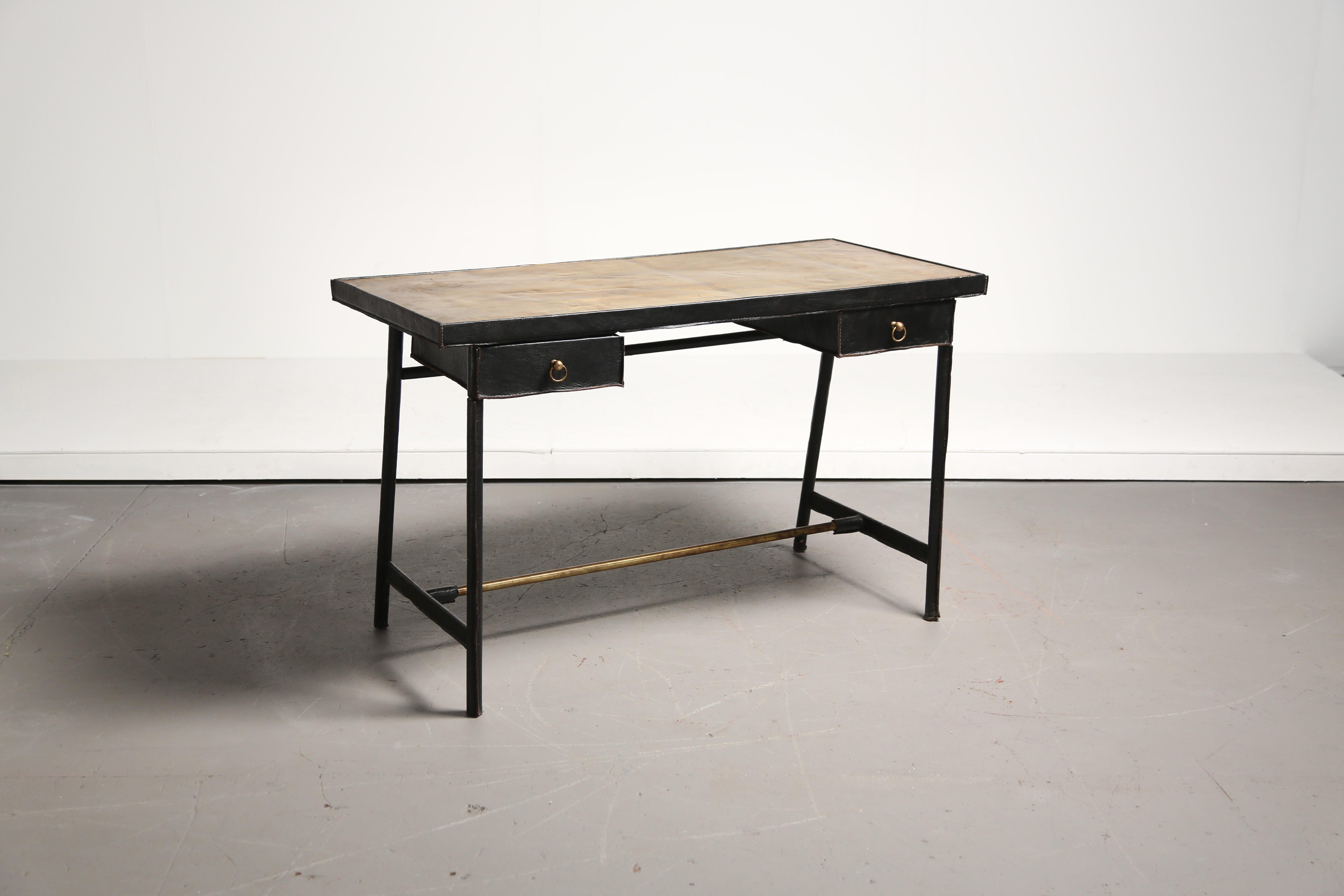 Scrivania rilegata in pelle e ottone, attribuita a Jacques Adnet, Francia.  Due cassetti estraibili.   La parte superiore in ottone presenta alcune ammaccature e impronte.   Può essere sostituito con pelle, ottone nuovo o un altro materiale, oppure