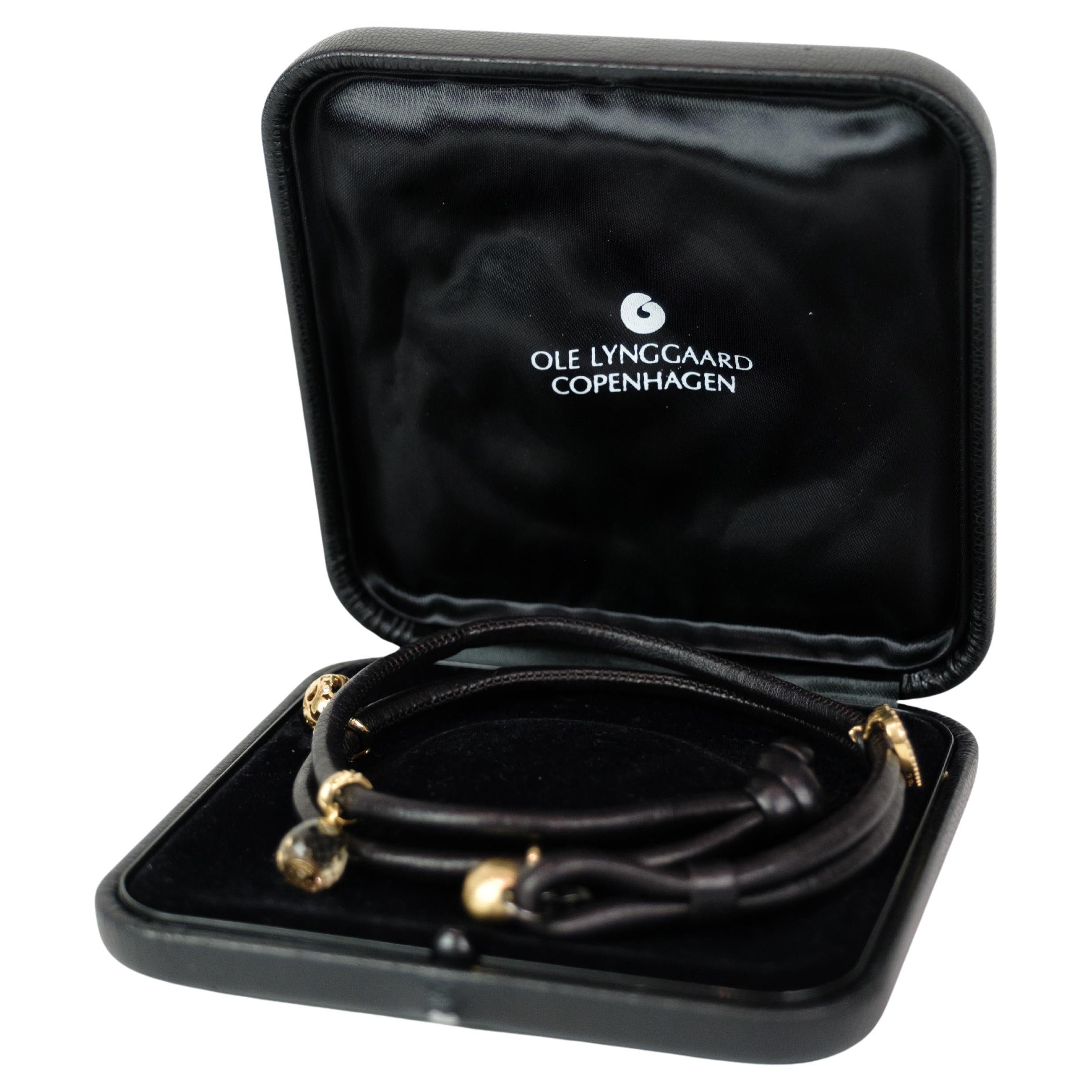 Bracciale in pelle di Ole Lynggaard, decorato con quattro diversi charme. Il bracciale presenta un cuore Sweet Drop in oro 18 carati con 30 diamanti taglio brillante, un Charm Sweet Drops in oro 18 carati con 6 diamanti taglio brillante, un charm a