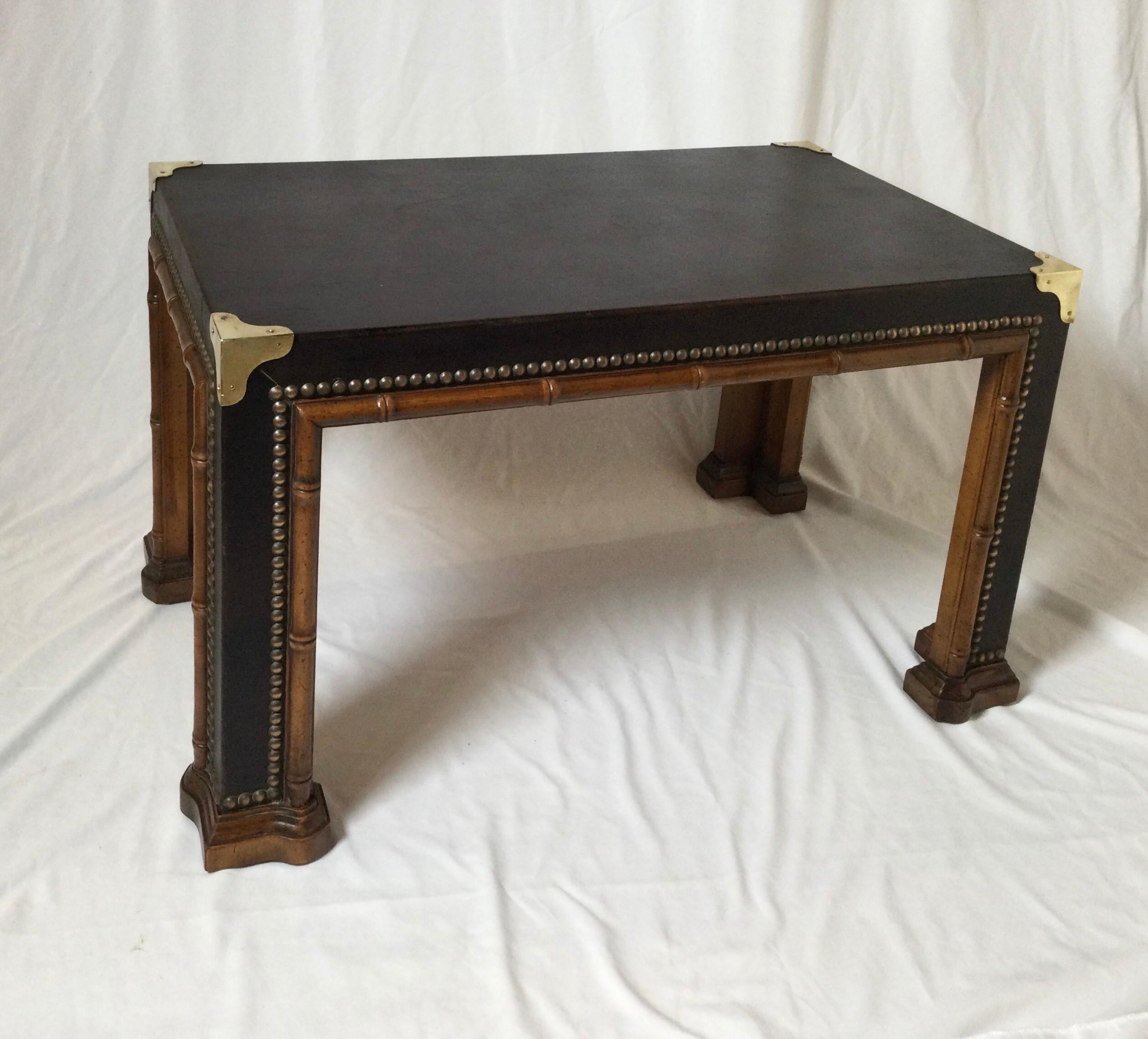 Vintage leather covered cocktail table with faux carved bamboo and brass trim. The tabaco color leather with brass nail head trim with brass corner pieces. Smallish size at 30 inches wide, 18 inches deep, 17.5 inches tall.
