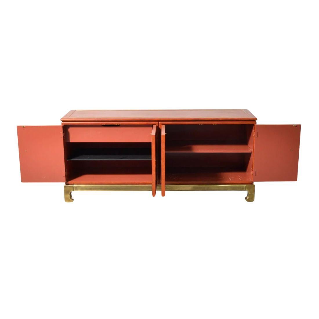 Questo mobile originale Mastercraft in pelle e ottone è uno splendido pezzo vintage prodotto negli Stati Uniti. La credenza è caratterizzata da una ricca pelle marrone rossastra all'esterno con ferramenta in ottone e piedi in stile Ming Ming con