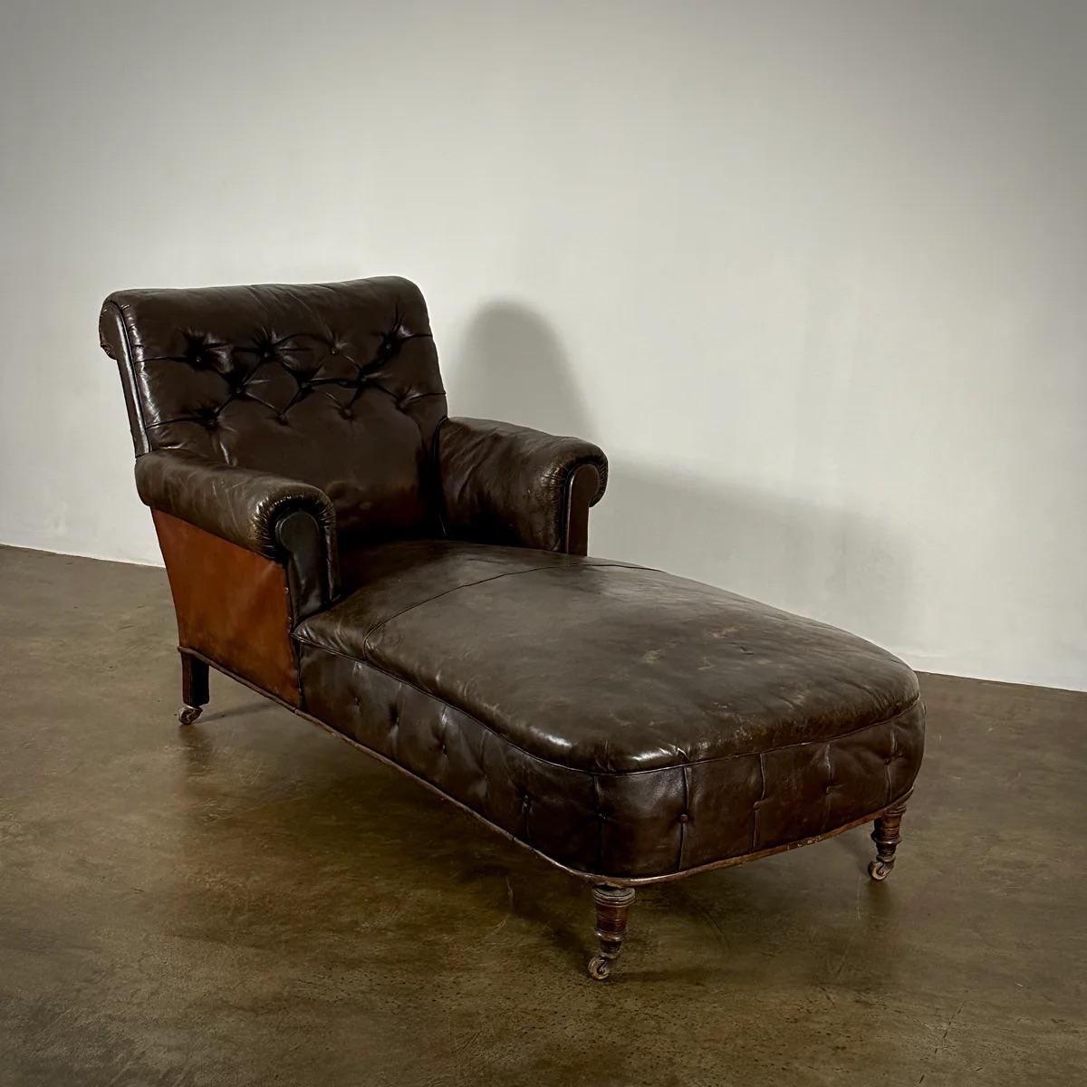 This 19th-century English leather buttoned daybed exudes an air of historic elegance with its deep chestnut brown leather, beautifully aged to showcase a rich patina. The daybed features a scrolled back, matching scrolled arms, and elegantly turned
